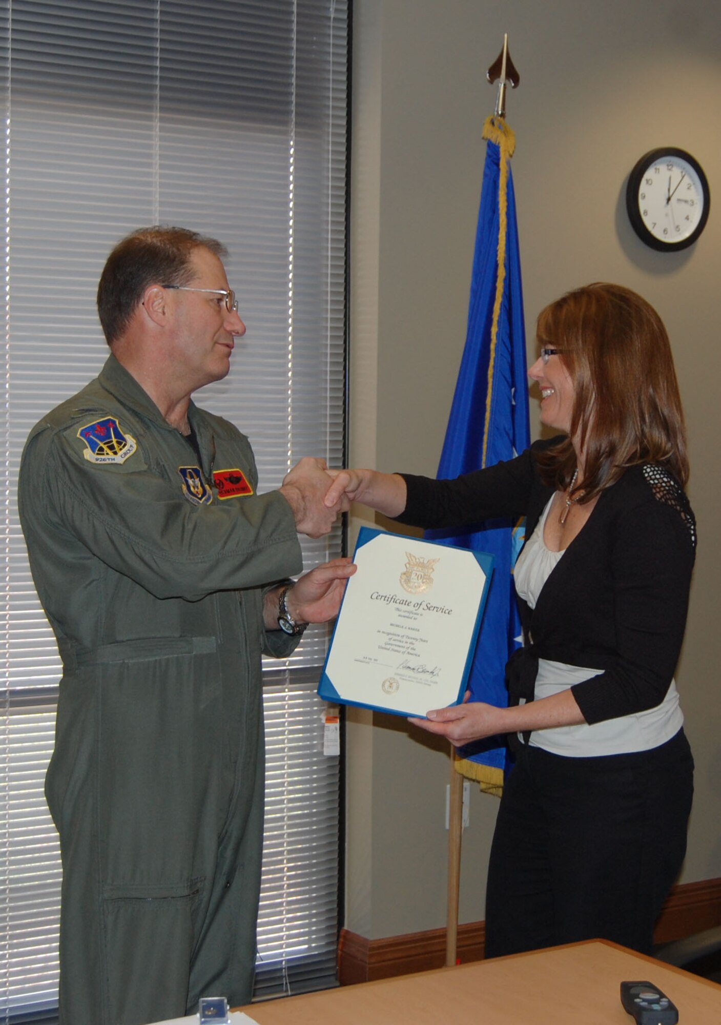 NELLIS AIR FORCE BASE, Nev. -- (Right) Michele Baker, 926th Group budget officer, is presented with a certificate of service for 20 years of service in the government of the United States by Col. Herman Brunke, 926th GP commander, March 16. (U.S. Air Force photo/Capt. Jessica Martin)