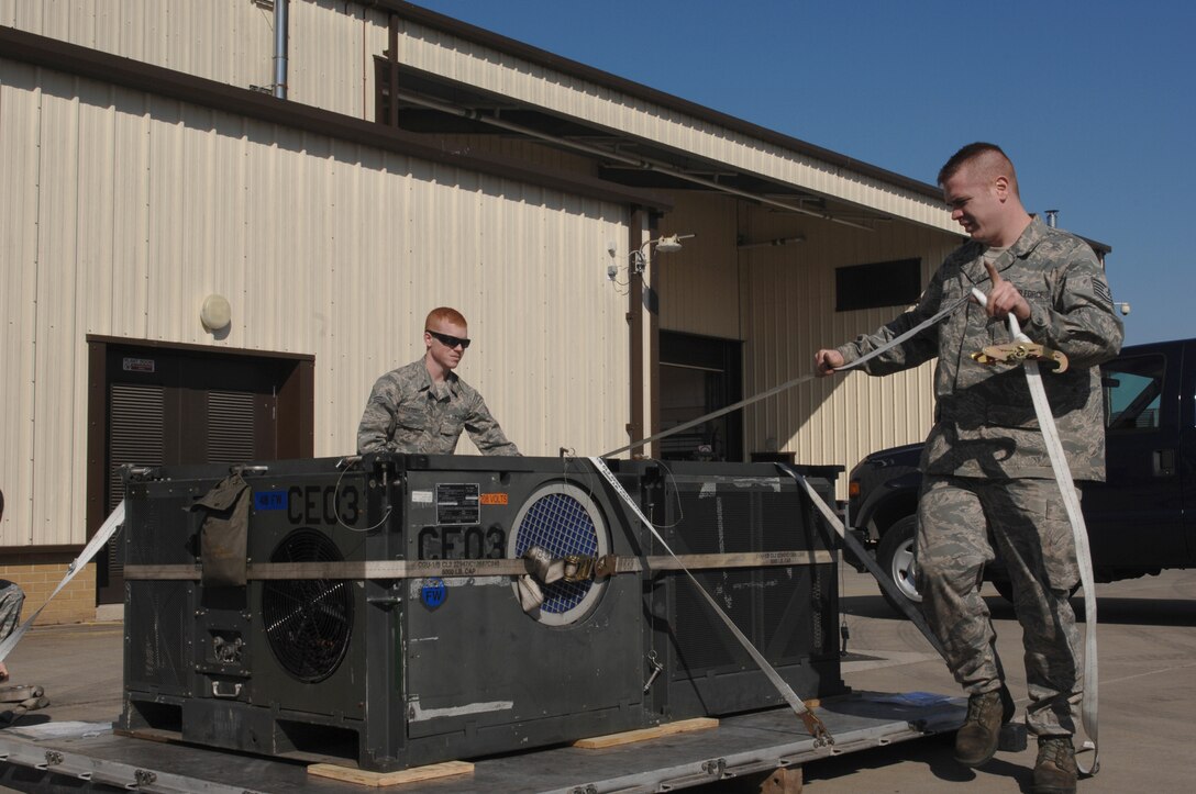 Tech. Sgt. Eric Ives, 48th Logistics Readiness Squadron, cargo team lead and Senior Airman Kevin Luebbert, 48th LRS, cargo team member, secures an air conditioning unit for deployment processing at RAF Lakenheath, England, March 19, 2011. Units from the 48th Fighter Wing are currently conducting pre-deployment procedures in support of Operation Odyssey Dawn.  The 48th Fighter Wing provides all-weather, day or night air superiority and air-to-ground precision combat capability as well as combat search and rescue. (U.S. Air Force photo by Tech. Sgt. Lee A. Osberry Jr./Released)