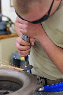 WHITEMAN AIR FORCE BASE, Mo. -- Airman 1st Class Steven Evanitus, 509th Maintenance Squadron hydraulic systems journeyman, grinds a rivet off a torque tube from a B-2 Spirit brake system March 22, 2011. Airman Evanitus removed the rivet to take a precision measurement during the repair of a B-2 brake system. (U.S. Air Force photo by Tech. Sgt. Charles Larkin Sr)