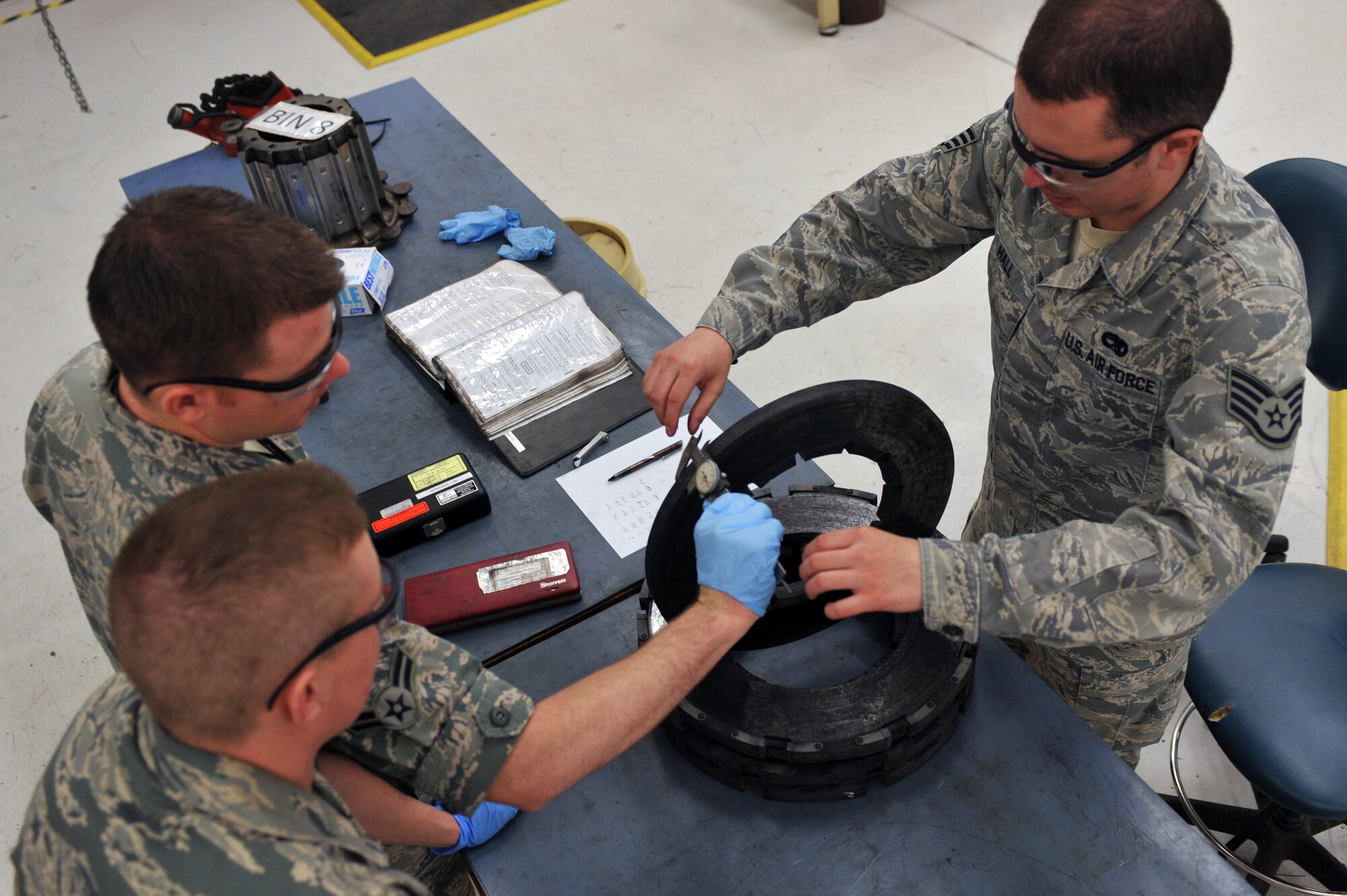 WHITEMAN AIR FORCE BASE, Mo. -- Staff Sgt. David Hall (right), Airman 1st Class Scott Whitney (top left) and Airman 1st Class Travis Dowler (bottom left), 509th Maintenance Squadron hydraulic systems repair technicians, measure a heat stack of a B-2 Spirit brake system March 22, 2011. Sergeant Hall instructed Airman Whitney and Airman Dowler on proper repair procedures for the B-2's brake system. (U.S. Air Force photo by Tech. Sgt. Charles Larkin Sr)