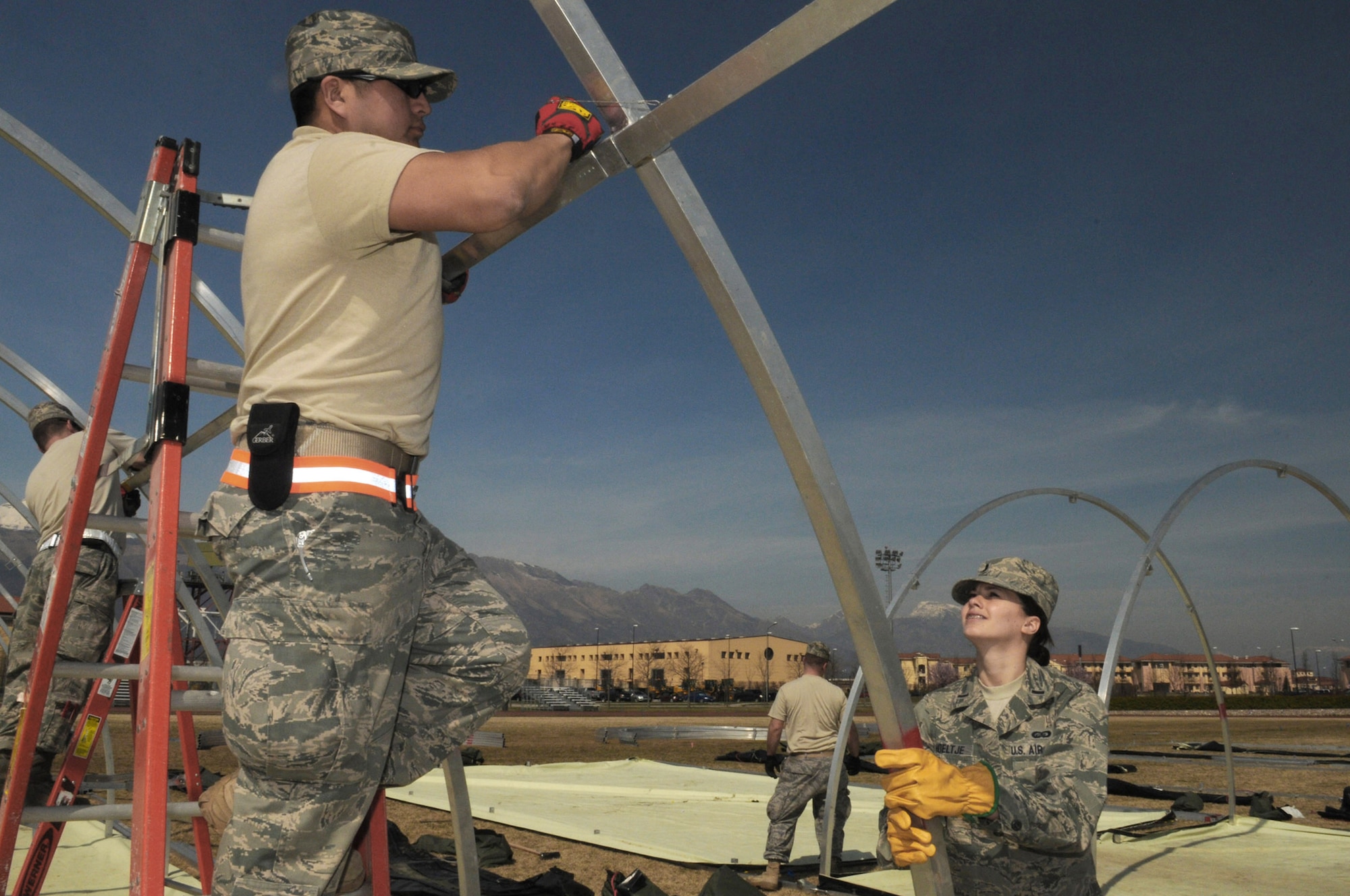 Tech. Sgt. Selvin Hudson and 1st Lt. Elizabeth Hoeltje assemble tents March 22, 2011, at Aviano Air Base, Italy, to house contingency personnel arriving there in support of Operation Odyssey Dawn. Sergeant Hudson is a structural craftsman assigned to the 48th Civil Engineer Squadron at Royal Air Force Lakenheath, England. Lieutenant Hoeltje is an executive officer with the 31st Mission Support Group. (U.S. Air Force photo/Staff Sgt. Nadine Y. Barclay)