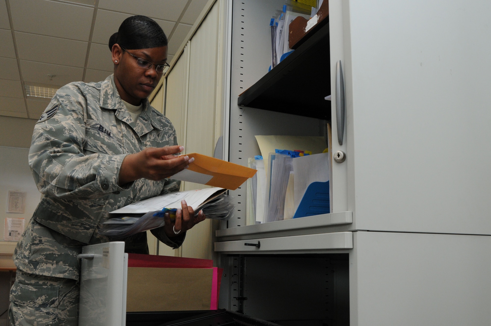 U.S. Air Force Senior Airman Erica Elam, 48th Force Support Squadron passport agent, files applications at the passport office at RAF Lakenheath, England, March 23. Airman Elam was nominated for a liberty spotlight because she portrayed the core value of 'Service Before Self'. (U.S. Air Force photo by Senior Airman Eboni Reams/Released)