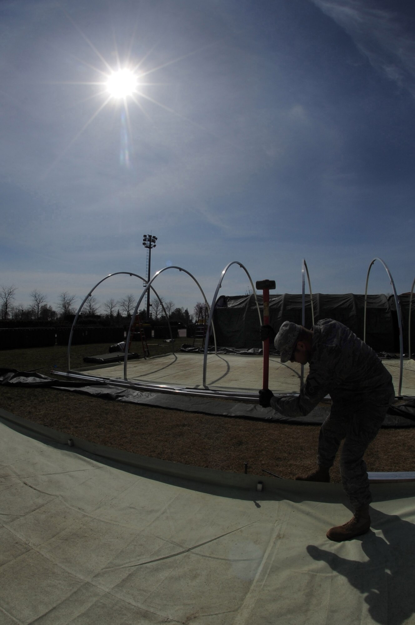 Master Sgt. Anthony Schultz, 31st Civil Engineer Squadron, hammers in an Alaskan small shelter tent stake March 22, 2011, as part of a tent city buildup for contingency personnel arriving at Aviano Air Base, Italy, in support of Operation Odyssey Dawn. Joint Task Force Odyssey Dawn is the U.S. Africa Command task force established to support the larger international response to the unrest in Libya.  A broad coalition of nations are partnering to enforce U.N. Security Council Resolution (UNSCR) 1973, which authorizes all necessary means to protect civilians in Libya under threat of attack by Qadhafi regime forces.  JTF Odyssey Dawn is commanded by Admiral Samuel J. Locklear, III. (U.S. Air Force photo/ Staff Sgt. Nadine Y. Barclay)