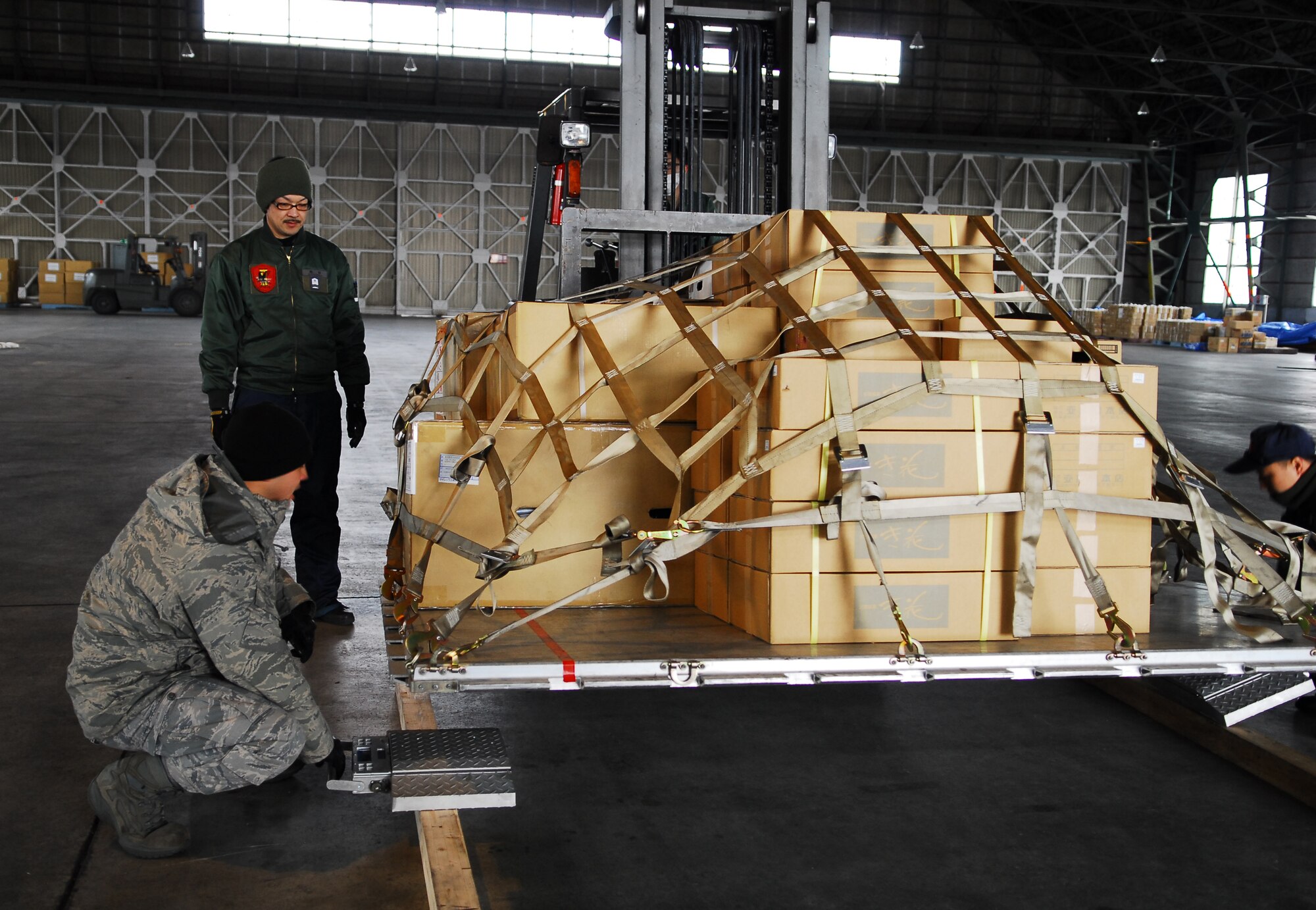 CHITOSE AIR BASE, Japan -- Staff Sgt. Shaun McCall, a combat mobility flight rigger from the 374th Logistics Readiness Squadron, works with Japan Air Self-Defense Force members at Chitose Air Base, Japan, to weigh a pallet carrying humanitarian relief supplies March 23. The supplies were transported from the air base to Mitsushima, Japan, by members of the 36th Airlift Squadron from Yokota Air Base, Japan. (U.S. Air Force photo/Staff Sgt. Robin Stanchak)