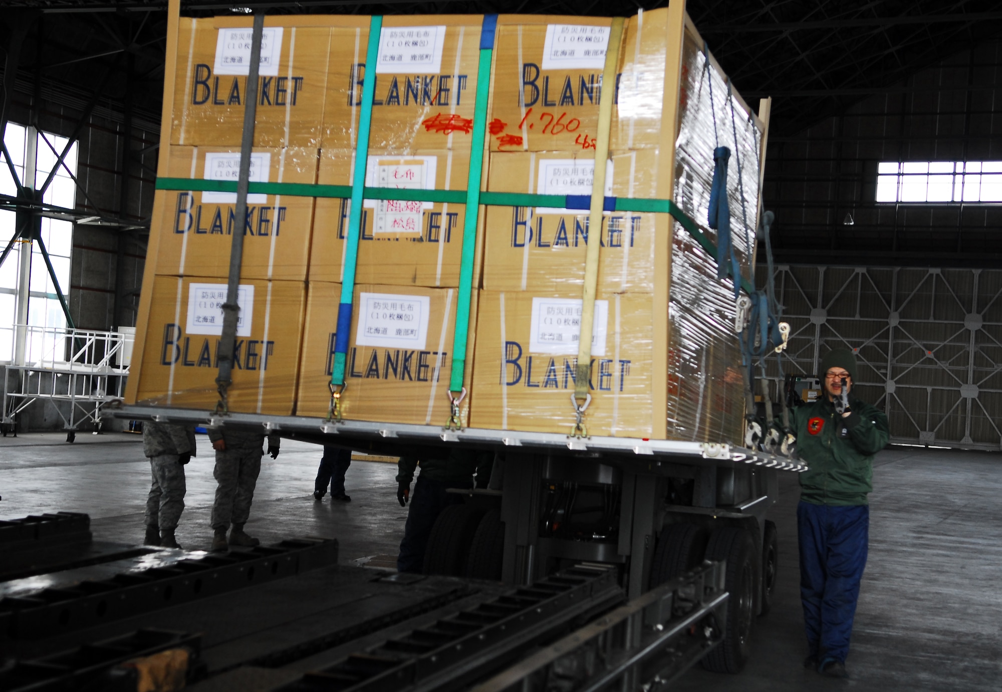 CHITOSE AIR BASE, Japan -- A member from the Japan Air Self-Defense Force at Chitose Air Base, Japan, guides a pallet carrying humanitarian relief supplies onto a k-loader March 23. The supplies were transported from the air base to Matsushima, Japan, by members of the 36th Airlift Squadron from Yokota Air Base, Japan. (U.S. Air Force photo/Staff Sgt. Robin Stanchak)