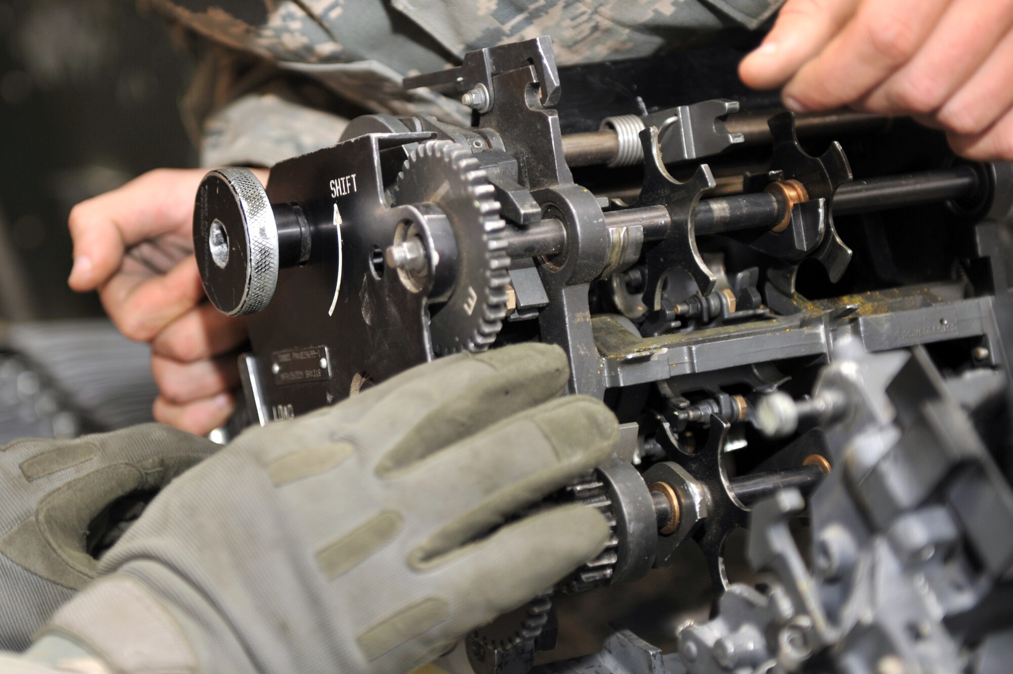 Members from the 455th Expeditionary Maintenance Squadron Ammunition Supply Point connect the linkless ammunition loading system to the replenisher table at Bagram Airfield, Afghanistan, March 23, 2011. This allows cycling of 20 millimeter rounds for inventory and inspection. (U.S. Air Force photo by Senior Airman Sheila deVera)