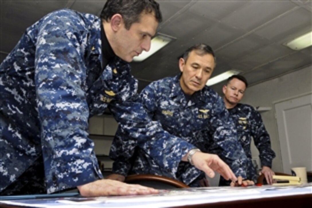 U.S. Navy Vice Adm. Harry B. Harris Jr. receives an overnight situation report from Lt. Cmdr. Kenneth "Max" Klima to support Joint Task Force Odyssey Dawn aboard the USS Mount Whitney in the Mediterranean Sea, March 24, 2011. The task force is the U.S. Africa Command task force providing operational and tactical command and control of U.S. military forces supporting the international response to the unrest in Libya. Harris is the Joint Force Maritime Component commander aboard the Mount Whitney.