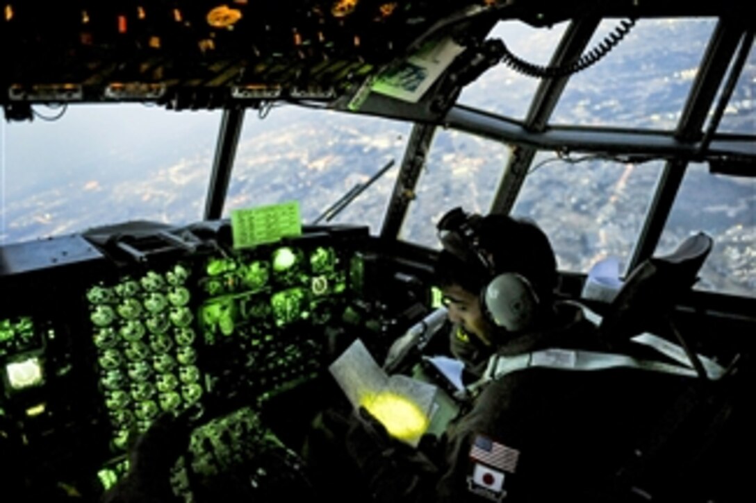 U.S. Air Force Capt. Yuri Batten looks at a map while flying a C-130 Hercules filled with medical supplies over Yokota, Japan, on March 19, 2011.  Batten, assigned to the 36th Airlift Squadron, is providing disaster relief for victims of the earthquake and tsunami in Japan.  