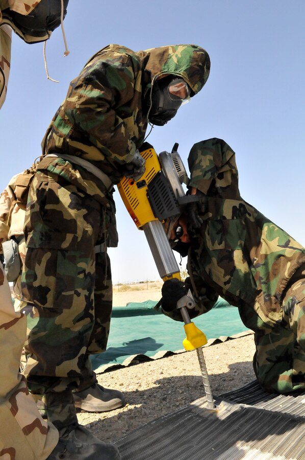 Sgt. Joshua Rookey, left, Marine Wing Support Squadron 371 expeditionary airfield technician, and Sgt. Julian Torres, MWSS-371 supply chief, drill a pad onto a newly formed expeditionary airfield at Laguna Army Air Field in Arizona, during a predeployment training exercise, March 24, 2011. Fourteen MWSS-371 Marines practiced setting pads down while wearing full mission oriented protective posture gear to simulate a deployment scenario. The pads allow aircraft to land with minimal foreign object debris, making it easier to land and refuel. The Sandsharks' predeployment training also overlapped with exercise Crown Joule 3, a Marine Aircraft Group 13 training cycle that helps pilots gain experience for the squadron's deployment to Afghanistan in fall.