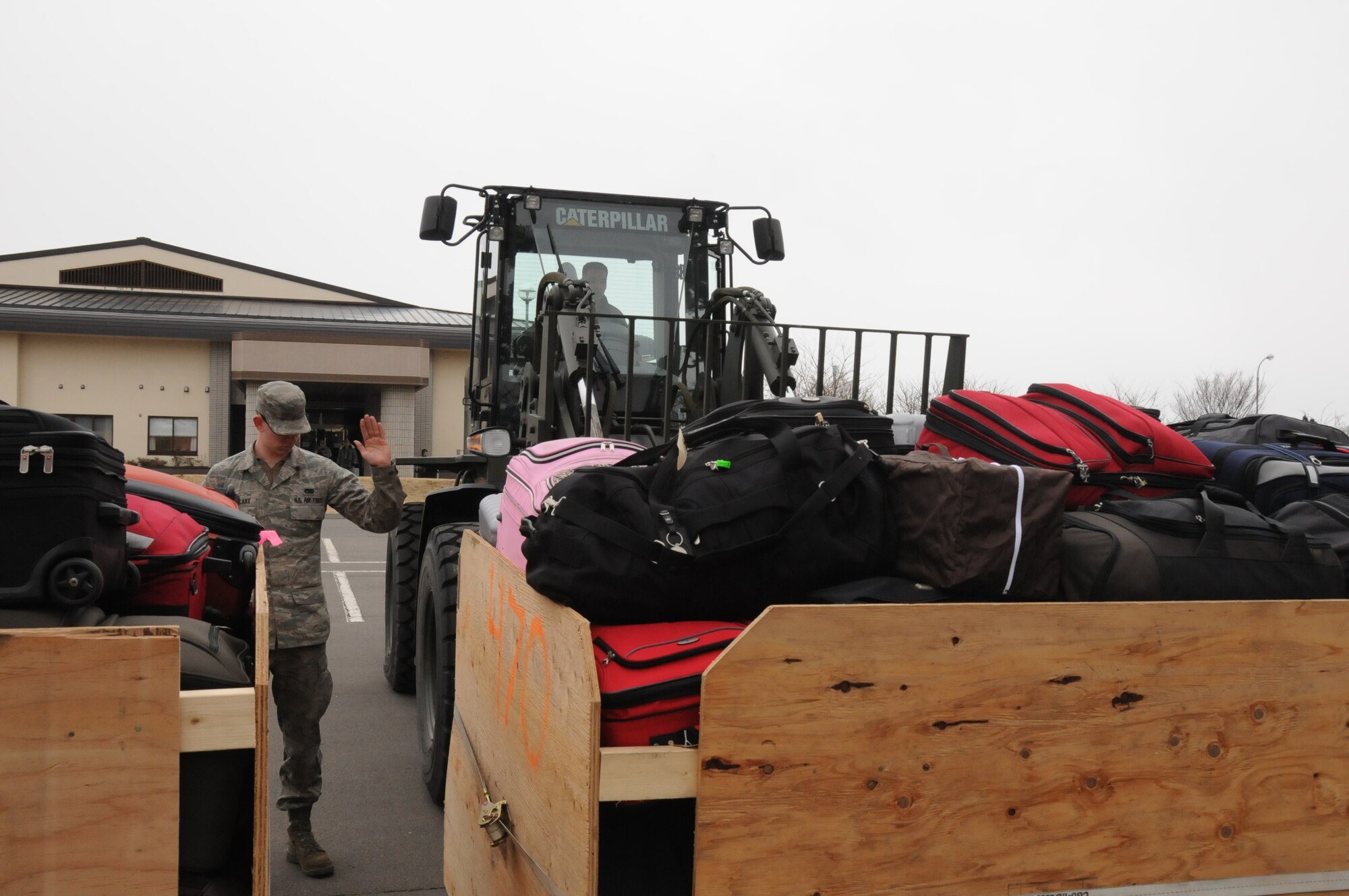 MISAWA AIR BASE, Japan -- Airman 1st Class Jeff Oberschlake, 35th Logistics Readiness Squadron, directs a forklift driver picking up luggage belonging to families voluntarily departing Misawa March 24. The LRS Airmen had developed a smooth process for handling the luggage that meant families did not have to wait a long times to check their baggage. Airman Oberschlake is from Hillsboro, Ohio. (U.S. Air Force photo by Staff Sgt. Rachel Martinez/Released)