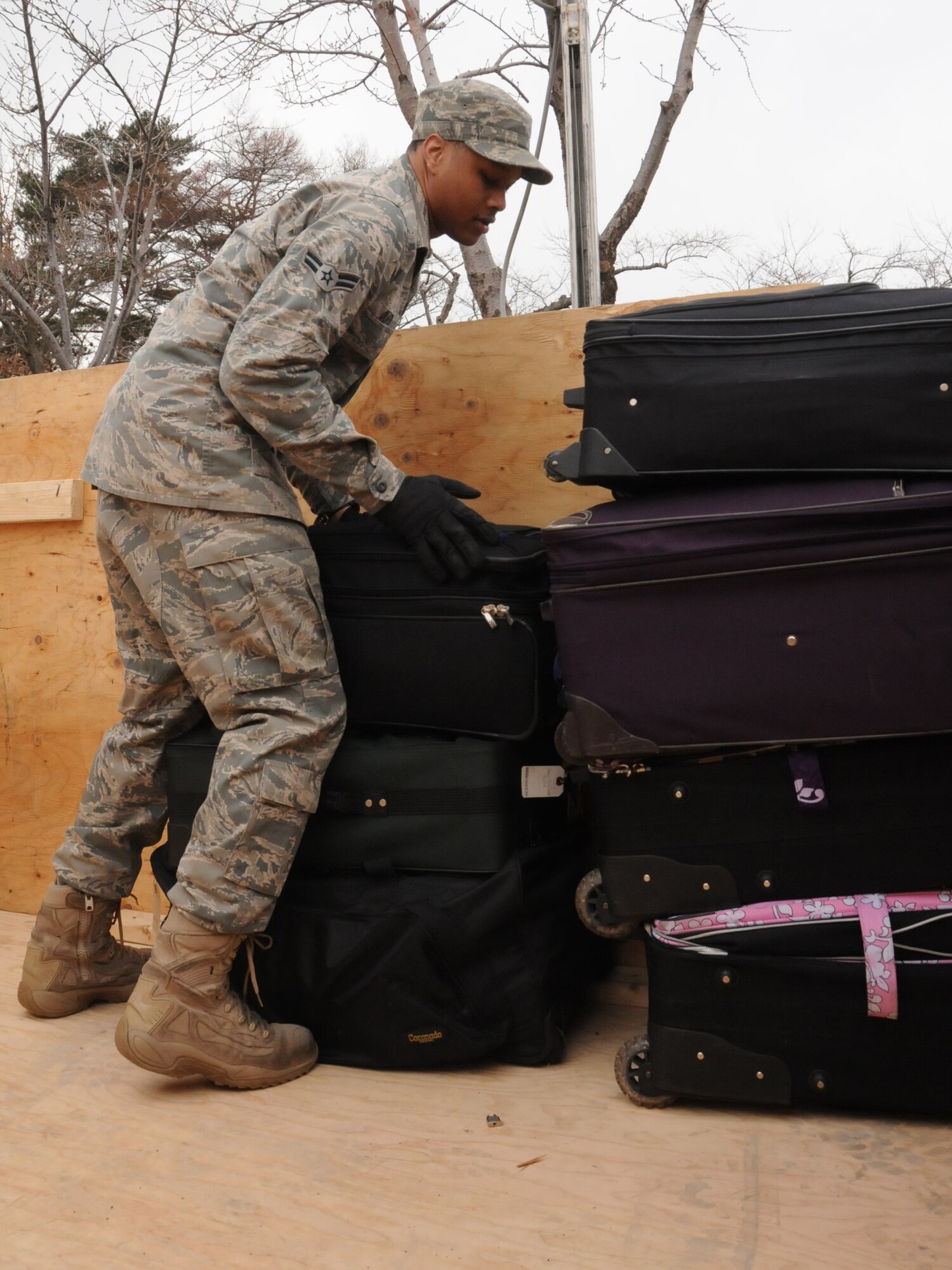 MISAWA AIR BASE, Japan ? Airman 1st Class Broderick Oliver, 35th Logistics Readiness Squadron, stacks luggage in a cargo bin outside the collocated club, March 24. Families leaving as part of the voluntary departure processed through the club before being bused to awaiting aircraft. (U.S. Air Force photo by Staff Sgt. Rachel Martinez/Released)