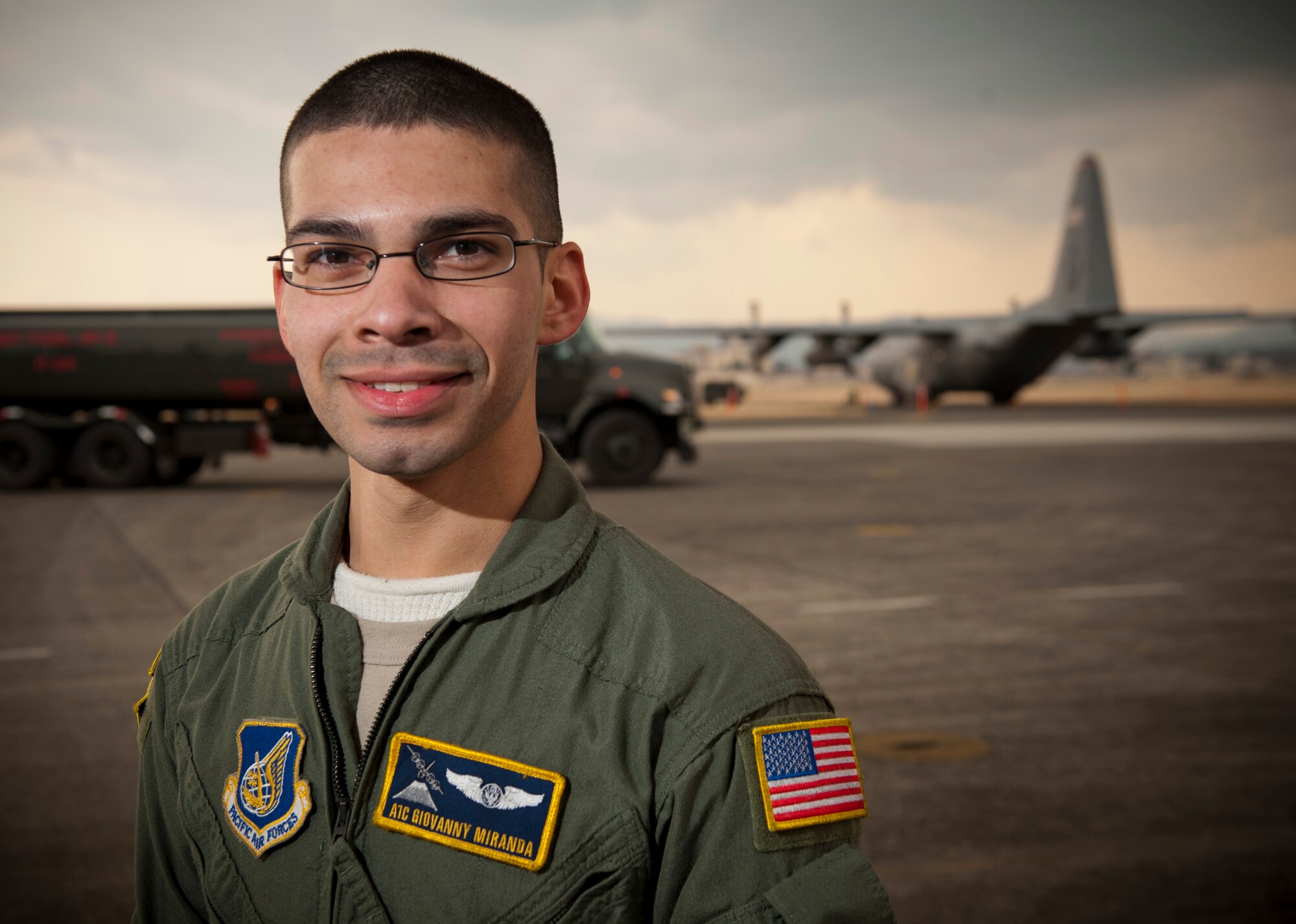 YOKOTA AIR BASE, Japan -- Airman 1st Class Giovanny Miranda, 36th Airlift Squadron loadmaster, stands in front of an R-11 fuel truck and a C-130 Hercules at Yokota Air Base, Japan, March 25. "It's completely amazing to be out in the field doing these missions where you know what you're doing is having an impact on the people who need it most." Airman Miranda hails from South Milwaukee, Wis. (U.S. Air Force photo/Staff Sgt. Samuel Morse)