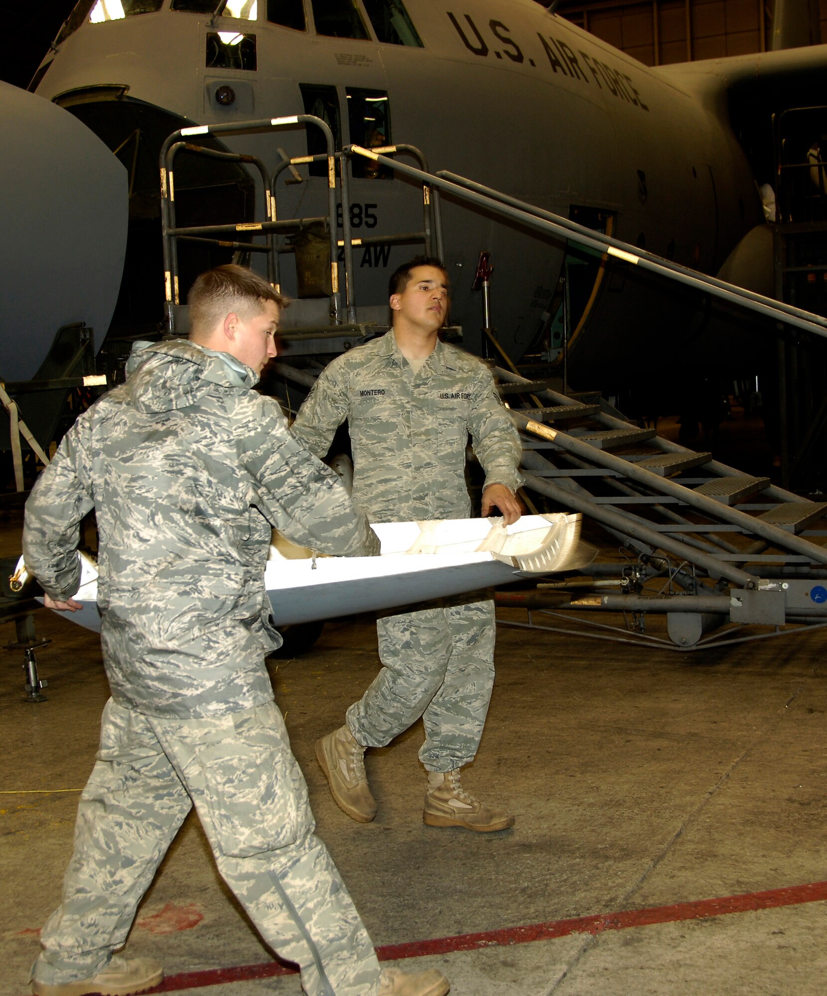 YOKOTA AIR BASE, Japan -- Airman 1st Class Travis Farr (left) and Staff Sgt. Alex Montero carry a C-130 Hercules forward landing gear door to a storage rack March 25, 2011. Removing the door helps electricians complete necessary repairs easier. The C-130 is undergoing routine maintenace in preparation to support Operation Tomodachi. Both Airmen are crew chiefs with the 374th Maintenance Squadron. (U.S. Air Force photo/ Staff Sgt. J.G. Buzanowski)
