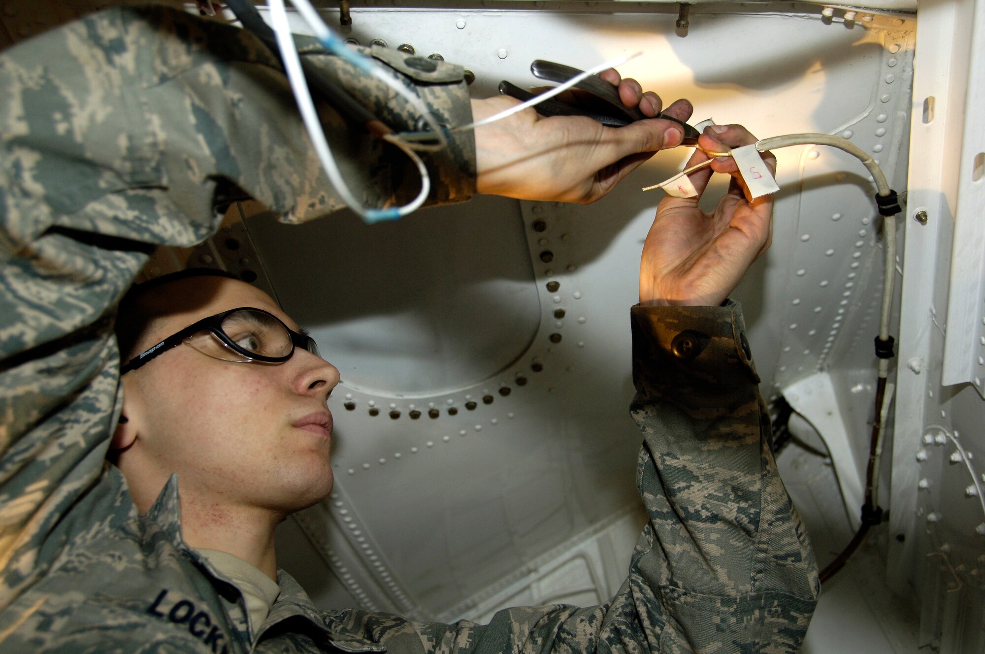YOKOTA AIR BASE, Japan -- Airman 1st Class Nolan Locken splices an uplock switch in the forward landing gear hatch of a C-130 Hercules March 25,2011. The C-130 is undergoing routine maintenace in preparation to support Operation Tomodachi. Airman Locken is a member of the 374th Maintenance Squadron. (U.S. Air Force photo/ Staff Sgt. J.G. Buzanowski)
