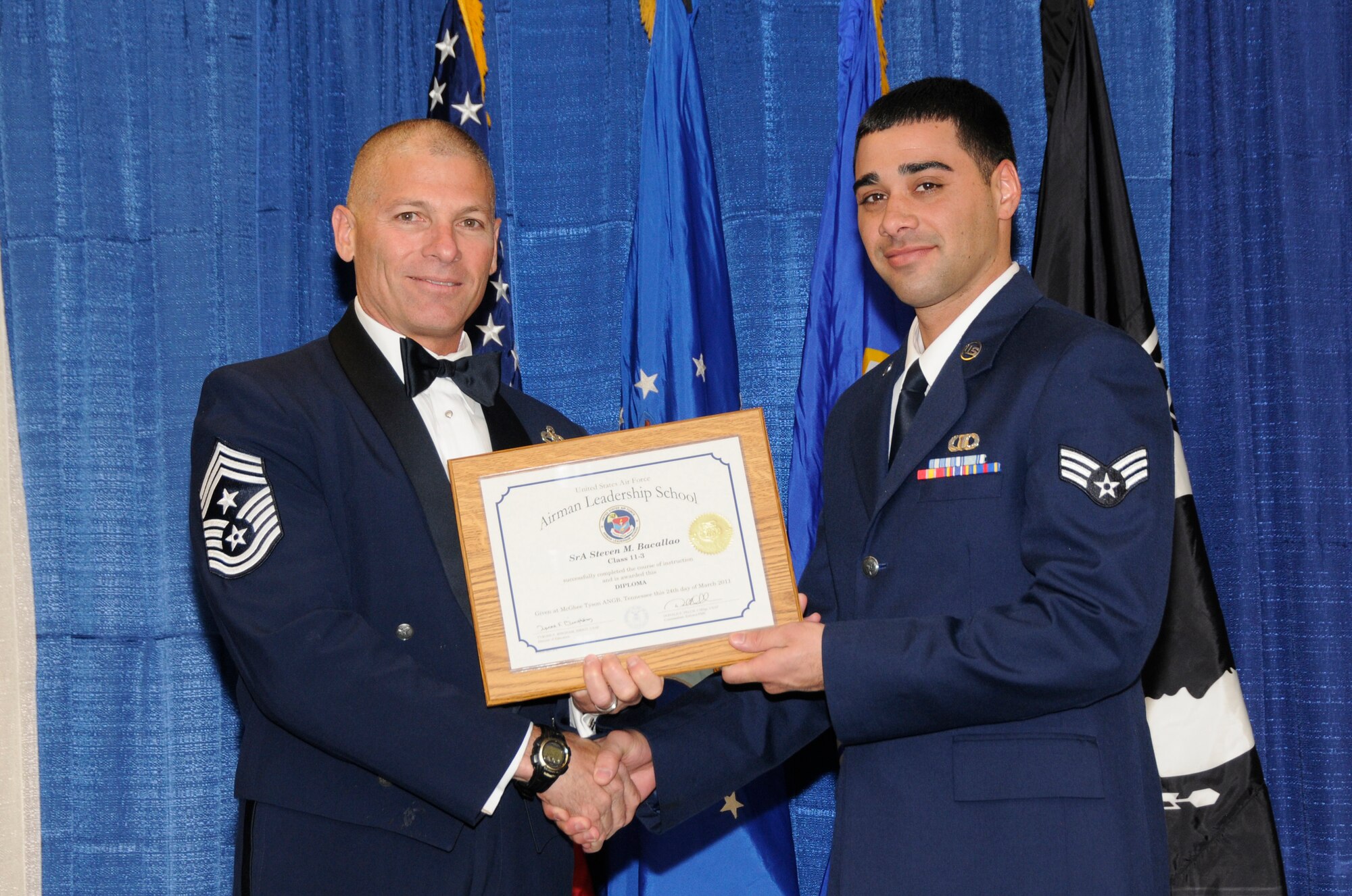 McGHEE TYSON AIR NATIONAL GUARD BASE, Tenn. - Senior Airman Steven M. Bacallao, right, an air traffic control specialist with the Wisconsin Air National Guard, receives the distinguished graduate award for Airman Leadership School Class 11-3 at The I.G. Brown Air National Guard Training and Education Center from Louisiana Command Chief Master Sgt. James E. Downing, Sr., March 24, 2011.  The distinguished graduate award is presented to students in the top ten percent of the class.  It is based on objective and performance evaluations, demonstrated leadership, and performance as a team player. (U.S. Air Force photo by Master Sgt. Kurt Skoglund/Released)