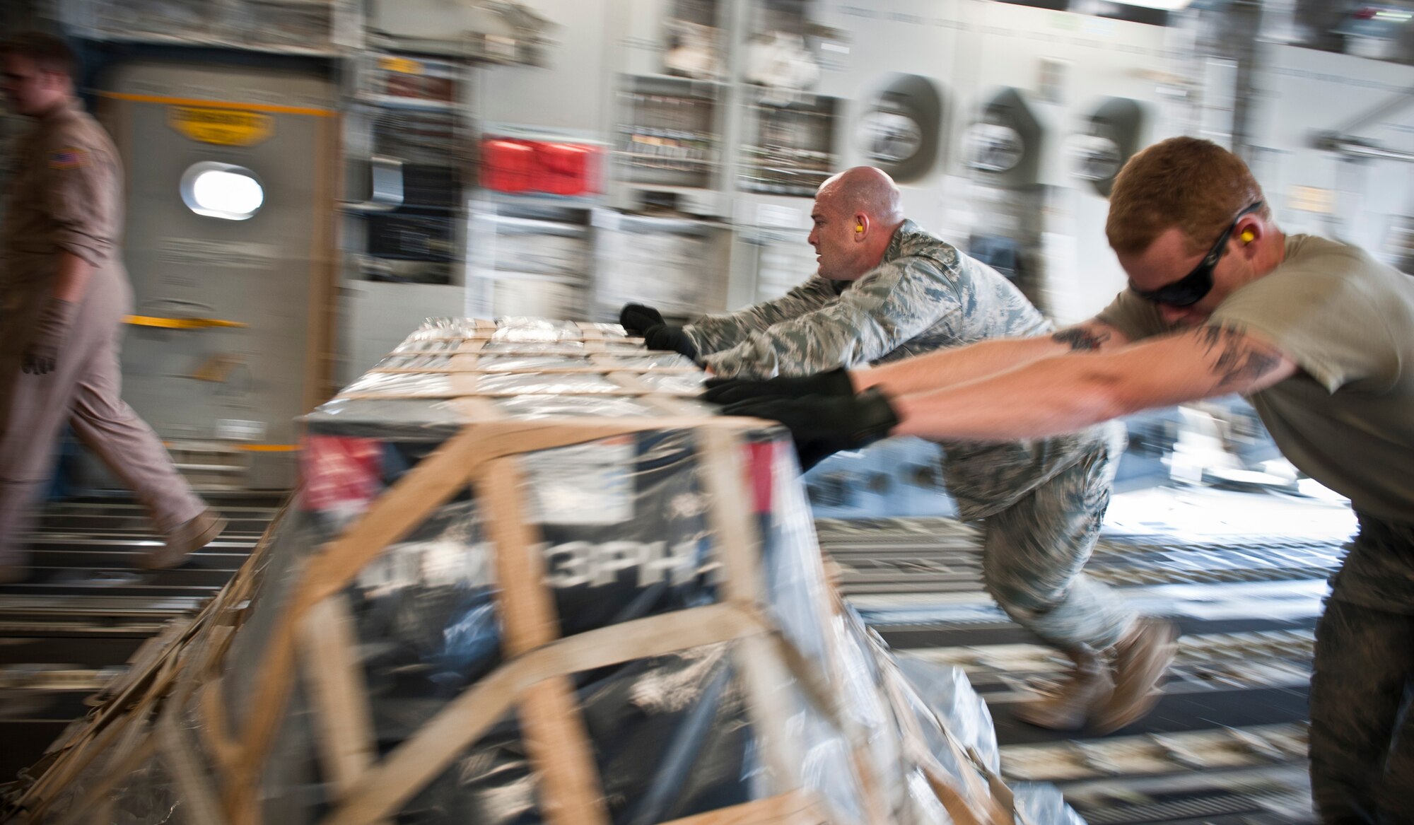 Airmen 1st Class Joseph Wruck, 23rd Logistics Readiness Squadron air transportation apprentice, and Benjamin Linton, 23rd LRS vehicle management and analysis apprentice, help load a pallet onto a C-17 Globemaster III March 24 at Moody Air Force Base, Ga. More than 30,000 pounds of cargo, containing six internal airlift/helicopter slingable container units and one pallet, was loaded onto the aircraft. (U.S. Air Force photo/Staff Sgt. Jamal D. Sutter)(RELEASED)