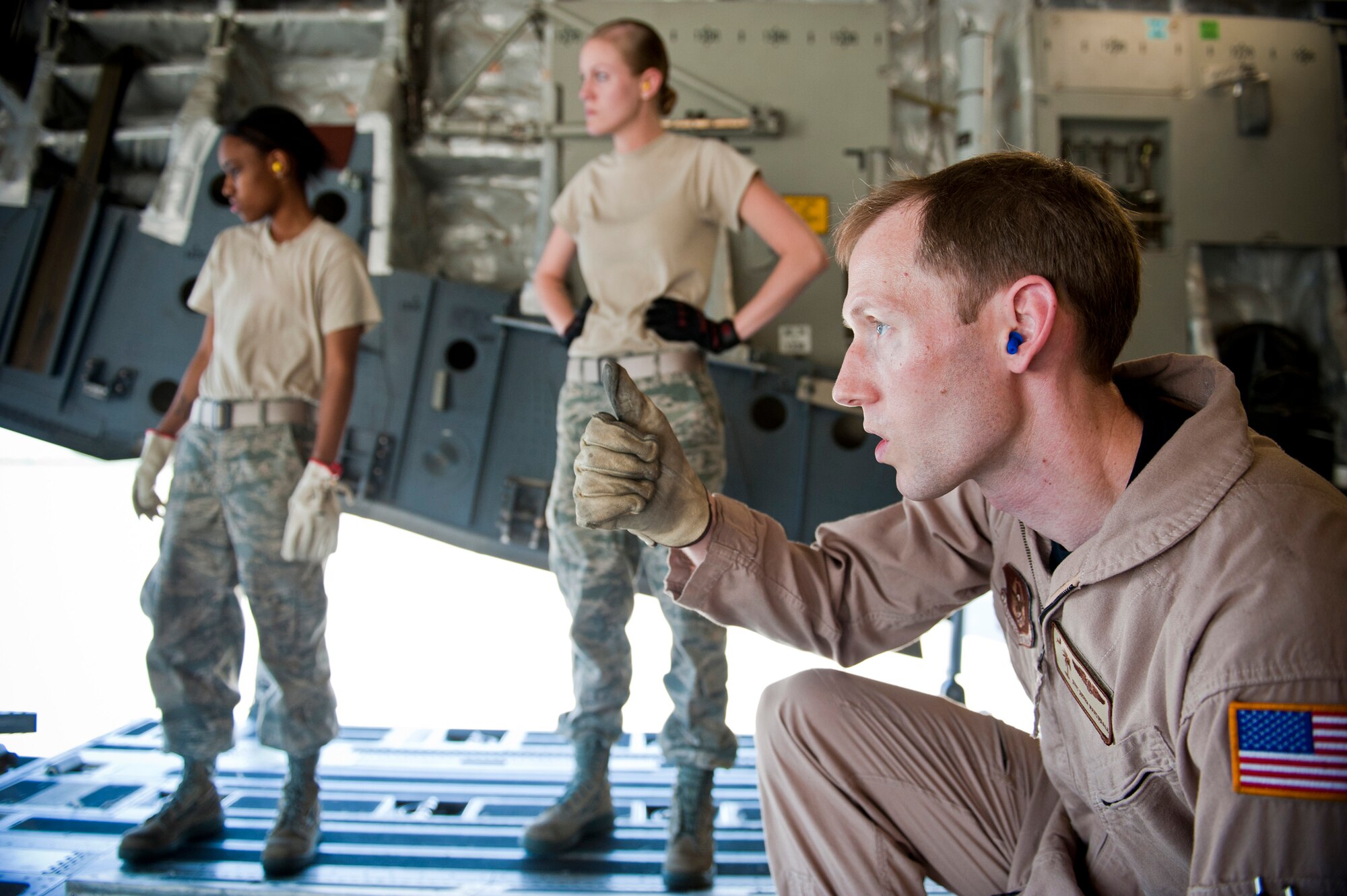 Staff Sgt. Derek Martindale, 317th Airlift Squadron C-17 loadmaster out of Charleston Air Force Base, S.C, signals to lift higher while loading cargo to a C-17 Globemaster III March 24 at Moody Air Force Base, Ga. A total team effort by loadmasters and various sections throughout the 23rd Logistics Readiness Squadron was required to securely load more than 30,000 pounds of cargo to the aircraft and get it in the air. (U.S. Air Force photo/Staff Sgt. Jamal D. Sutter)(RELEASED)