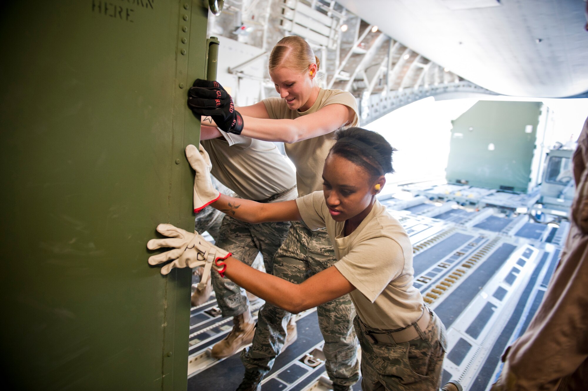 Senior Airman Brittany Bonhorst, 23rd Logistics Readiness Squadron supply journeyman, and Airman 1st Class LaTosha Ross, 23rd LRS supply apprentice, help secure cargo to a C-17 Globemaster III March 24 at Moody Air Force Base, Ga. For large loads, the 23rd LRS uses augmentees from various sections within the unit to assist in completing the mission. (U.S. Air Force photo/Staff Sgt. Jamal D. Sutter)(RELEASED)