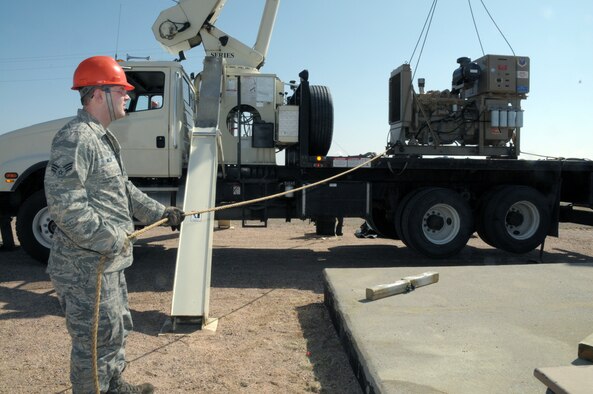 Senior Airman Bert Miller, 90th Missile Maintenance Squadron, holds the tagline of the new diesel engine that will replace the former unit as it's lifted off the truck to be lowered into place March 18. (U.S. Air Force photo by Blaze Lipowski)
