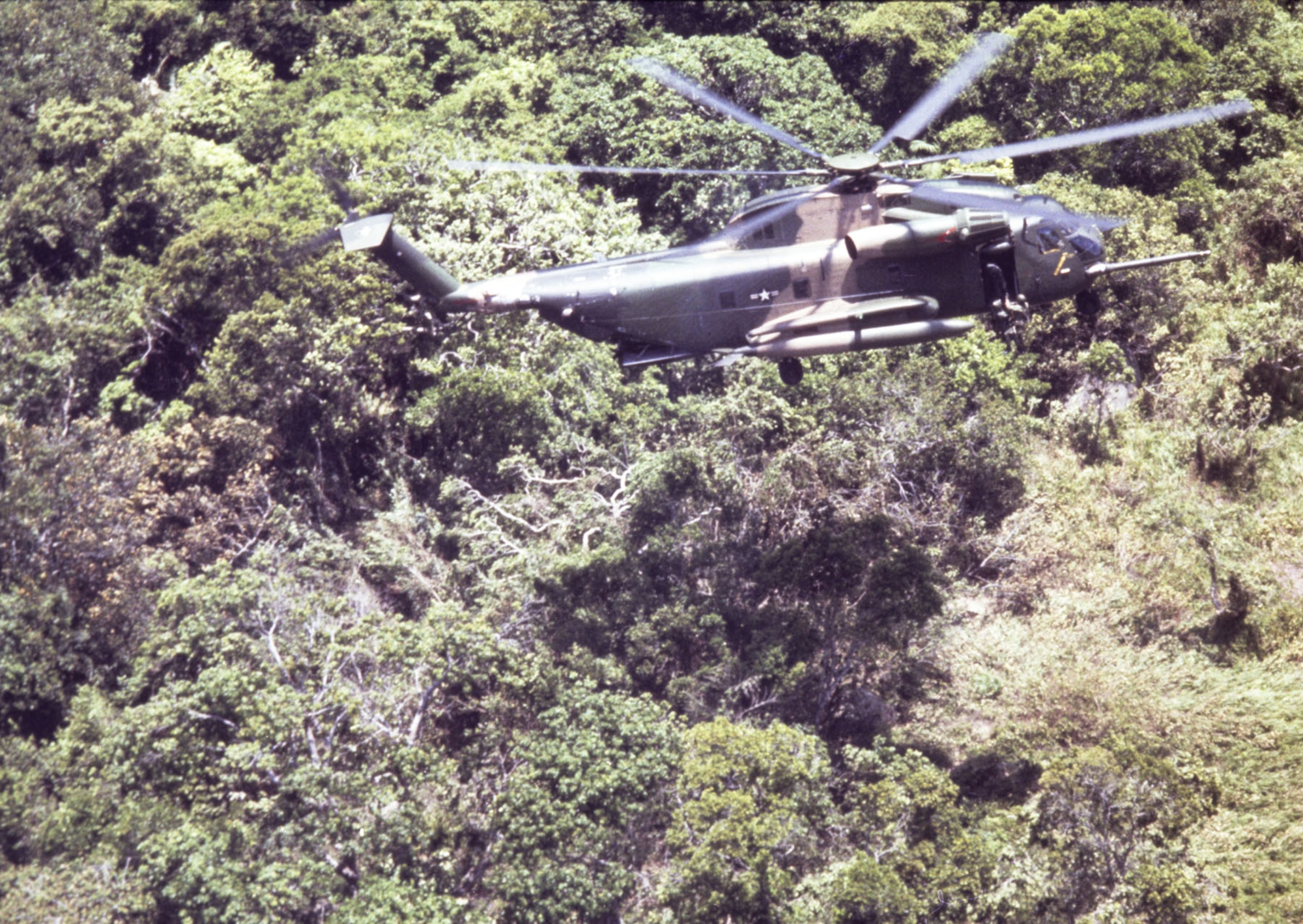 A U.S. Air Force pararescueman is lowered on a forest penetrator from a hovering 37th Aerospace Rescue and Recovery Squadron HH-53 helicopter during a rescue mission in Southeast Asia, June 1970. (U.S. Air Force photo)