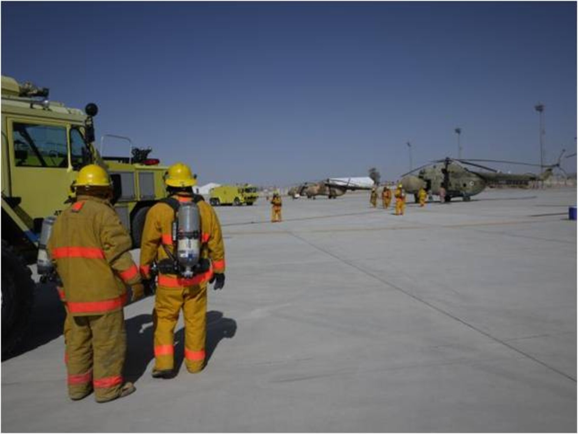 KHANDAR, Afghanistan - On March 24, members of Kandahar Air Wing Firefighters stand by at their vehicles ready to lend a hand during a real-time fire exercise evaluating the fire department’s proficiency in responding to a Mi-17 aircraft crash at Kandahar Airfield. (U.S. Air Force photo)