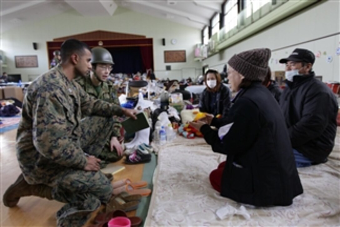 U.S. Marine Corps Capt. Vieet Rajan (left), with III Marine Expeditionary Force, speaks with survivors at a shelter facility inside Watariha Elementary School in Ishinomaki city, Miyagi prefecture, Japan, on March 23, 2011.  Rajan accompanied John V. Roos, the U.S. ambassador to Japan, and Commander of U.S. Pacific Command Adm. Robert F. Willard as they assisted in the delivery of relief supplies to displaced citizens at the shelter.  