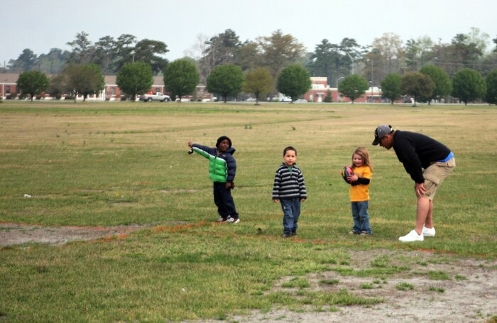 Lance Cpl. Rafeal Gomez, a supply clerk with Supply Management Unit, 2nd Supply Battalion, 2nd Marine Logistics Group, plays football with children during family day at the Goettge Field House aboard Camp Lejeune, N.C., March 26, 2011. During the event there were several stations in which children could win a gold medal. The stations consisted of football, golf and soccer.