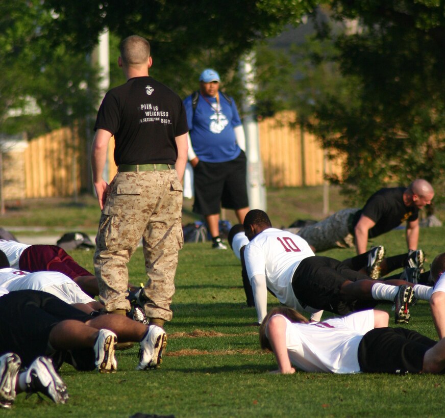 Football players in the Junior Rank Diamond Flight football camp execute push-ups with Marines Mar. 25. Marines participating in the camp led players in exercises, football drills and a leadership seminar in order to develop good character and discipline in the young men.