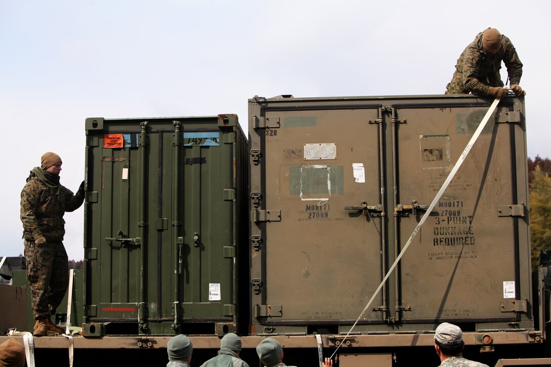 Marines with Marine Wing Support Squadron 171, attached to Combat Logistics Regiment 35, 3rd Marine Logistics Group, offload containers filled with field shower equipment here March 26. Service members with Joint Forces Land Component Command and Japan North East Army delivered and constructed the showers for internally displaced personnel at the Oshima Community Center.