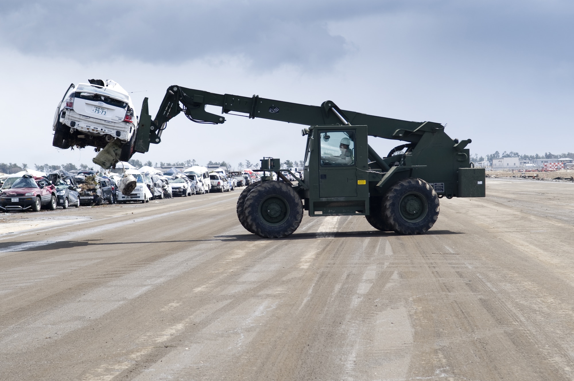SENDAI AIRPORT, Japan -- U.S. Marines from Combat Logistics Regiment 35, Camp Kinser, Okinawa help japanese workers remove damaged cars at Sendai Airport, March 26. The Marines are at Sendai Airport to support the people of Japan as part of Operation Tomodachi. (U.S. Air Force photo by/Master Sgt. Jeromy K. Cross)