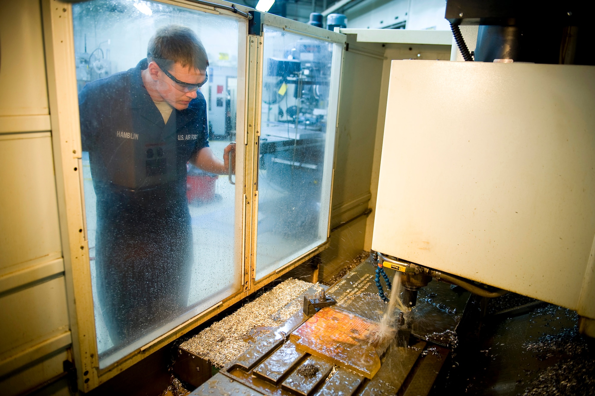YOKOTA AIR BASE, Japan -- Airman 1st Class Jeremy Hamblin, 374th Maintenance Squadron metals technician, watches closely as a computer numerical controller drills holes in a sheet of metal, which will be used to make a flange for Japanese relief worker here March 26. After completed, Australian engineers will pass them to Japanese relief workers who can use the newly created flanges to help cool down the nuclear reactors and help stabilize the nuclear power plant in Japan. (U.S. Air Force photo/Staff Sgt. Chad C. Strohmeyer)