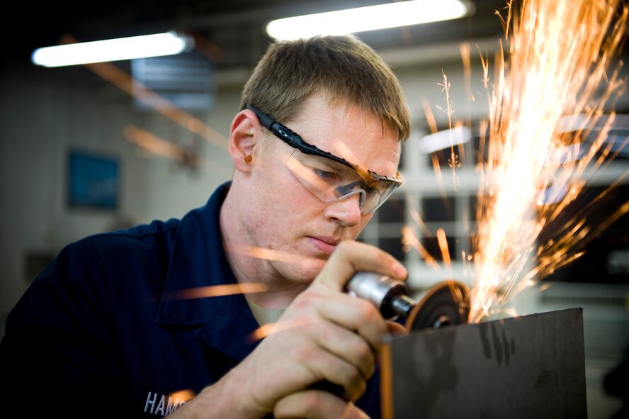 YOKOTA AIR BASE, Japan -- Airman 1st Class Jeremy Hamblin, 374th Maintenance Squadron metals technician, grinds a sheet of metal that will be used to make a flange here March 26. After completed, Australian engineers will pass them to Japanese relief workers who can use the newly created flanges to help cool down the nuclear reactors and help stabilize the nuclear power plant in Japan. (U.S. Air Force photo/Staff Sgt. Chad C. Strohmeyer)