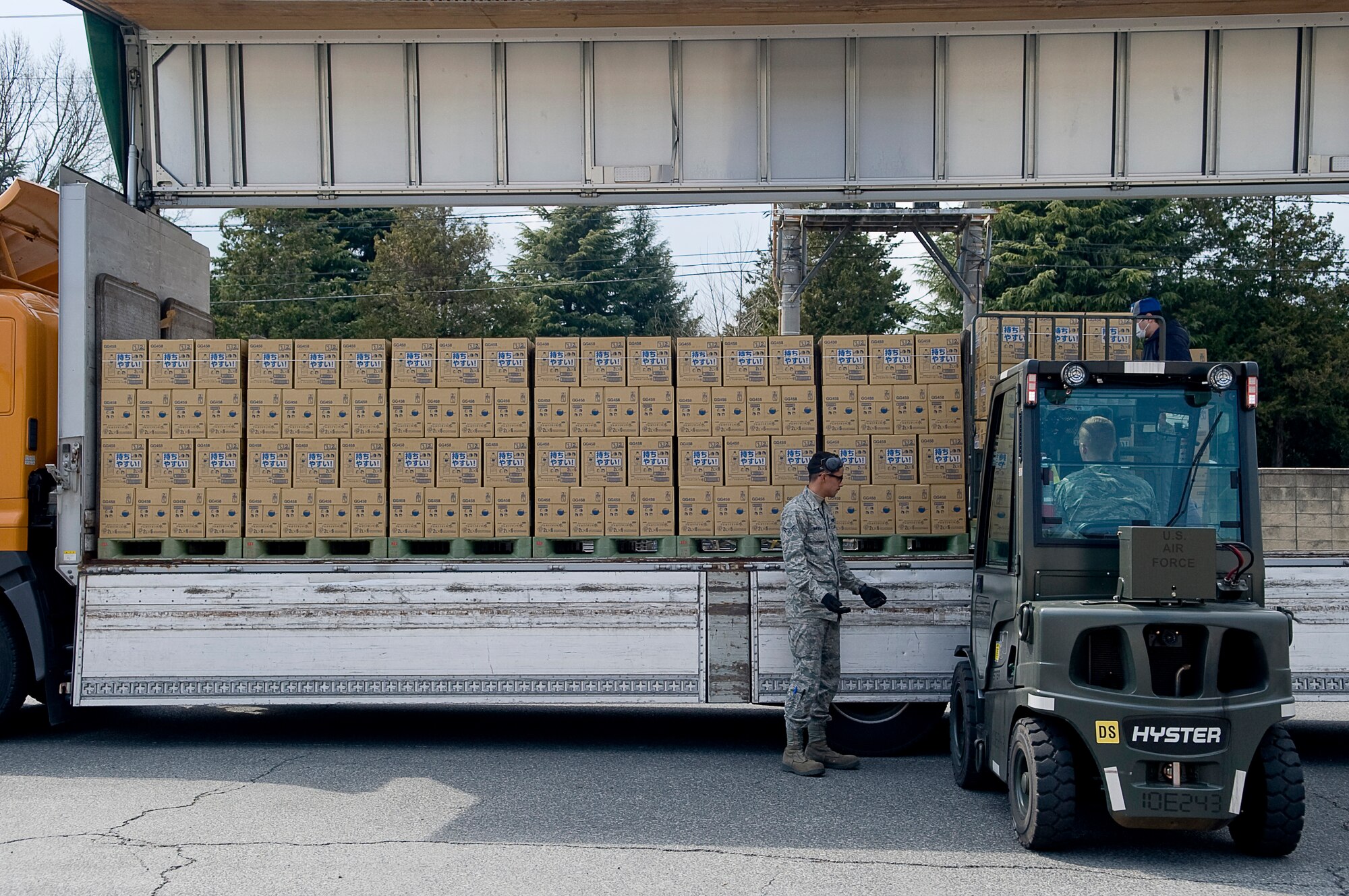 YOKOTA AIR BASE, Japan -- Airman 1st Class Tyler Mauga (spotter), and Senior Airman Steven Leydon (driver), 730th Air Mobility Squadron, unload pallets of water from a Japanese commercial truck here March 25. The Airmen of the 730th AMS have unloaded more than 1.5 million pounds of water to be airlifted in support of Operation Tomodachi. (U.S. Air Force photo by/Master Sgt. Jeromy K. Cross)