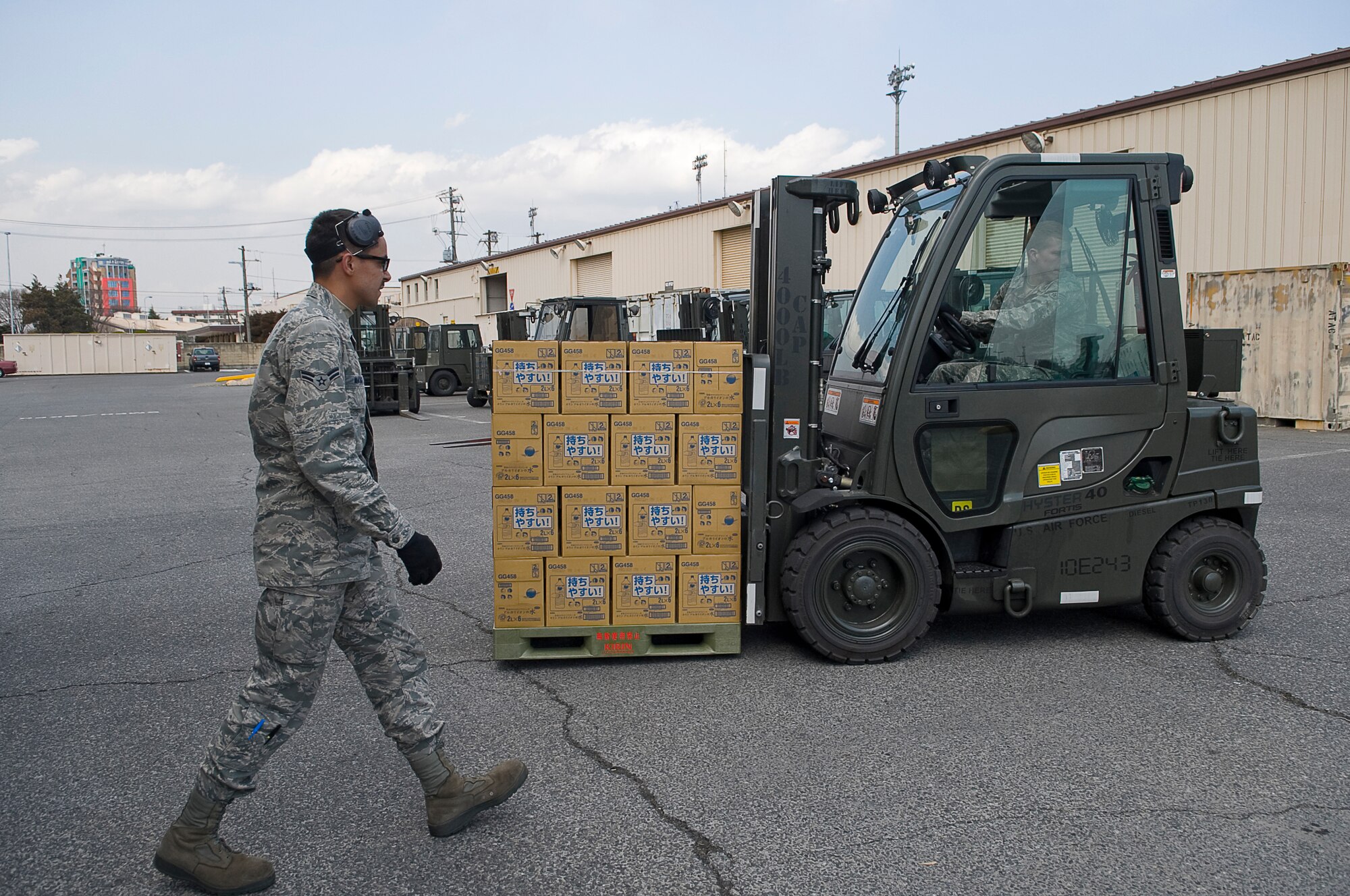 YOKOTA AIR BASE, Japan -- Airman 1st Class Tyler Mauga (spotter), and Senior Airman Steven Leydon (driver), 730th Air Mobility Squadron move a pallet of water to be configured for flight here March 25. The Airmen of the 730th AMS have prepared more than 1.5 million pounds of water to be airlifted in support of Operation Tomodachi. (U.S. Air Force photo by/Master Sgt. Jeromy K. Cross)