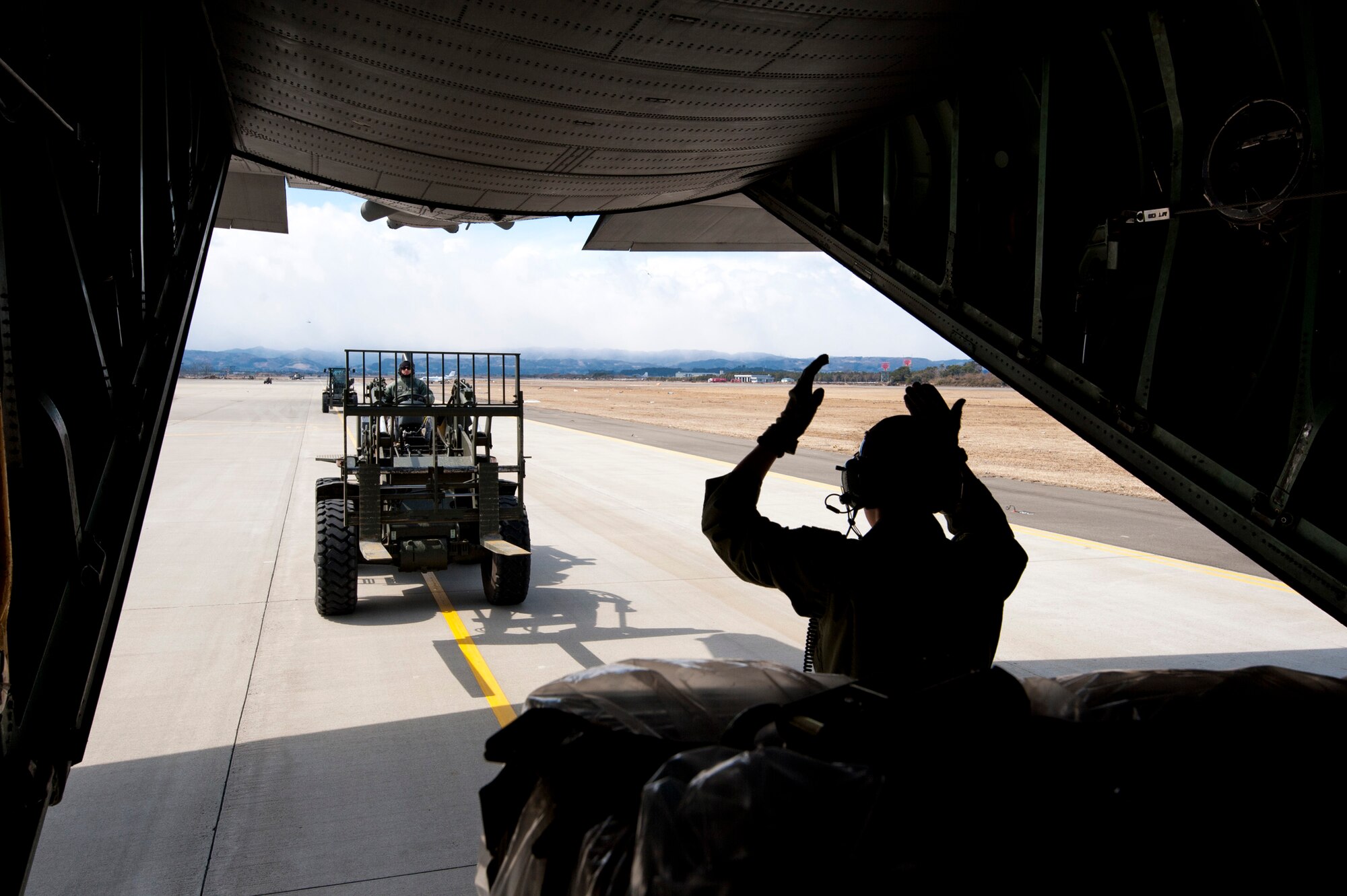 SENDAI AIRPORT, Japan -- Senior Airman Jordanna Wilson, 36th Airlift Squadron loadmaster, marshals a forklift to pickup pallets of water at Sendai Airport, Japan, March 26, 2011. Col. Otto Feather, 374th Airlift Wing commander, flew five pallets of potable water to Sendai Airport to be distributed to Japanese citizens in need. (U.S. Air Force photo/Staff Sgt. Samuel Morse)