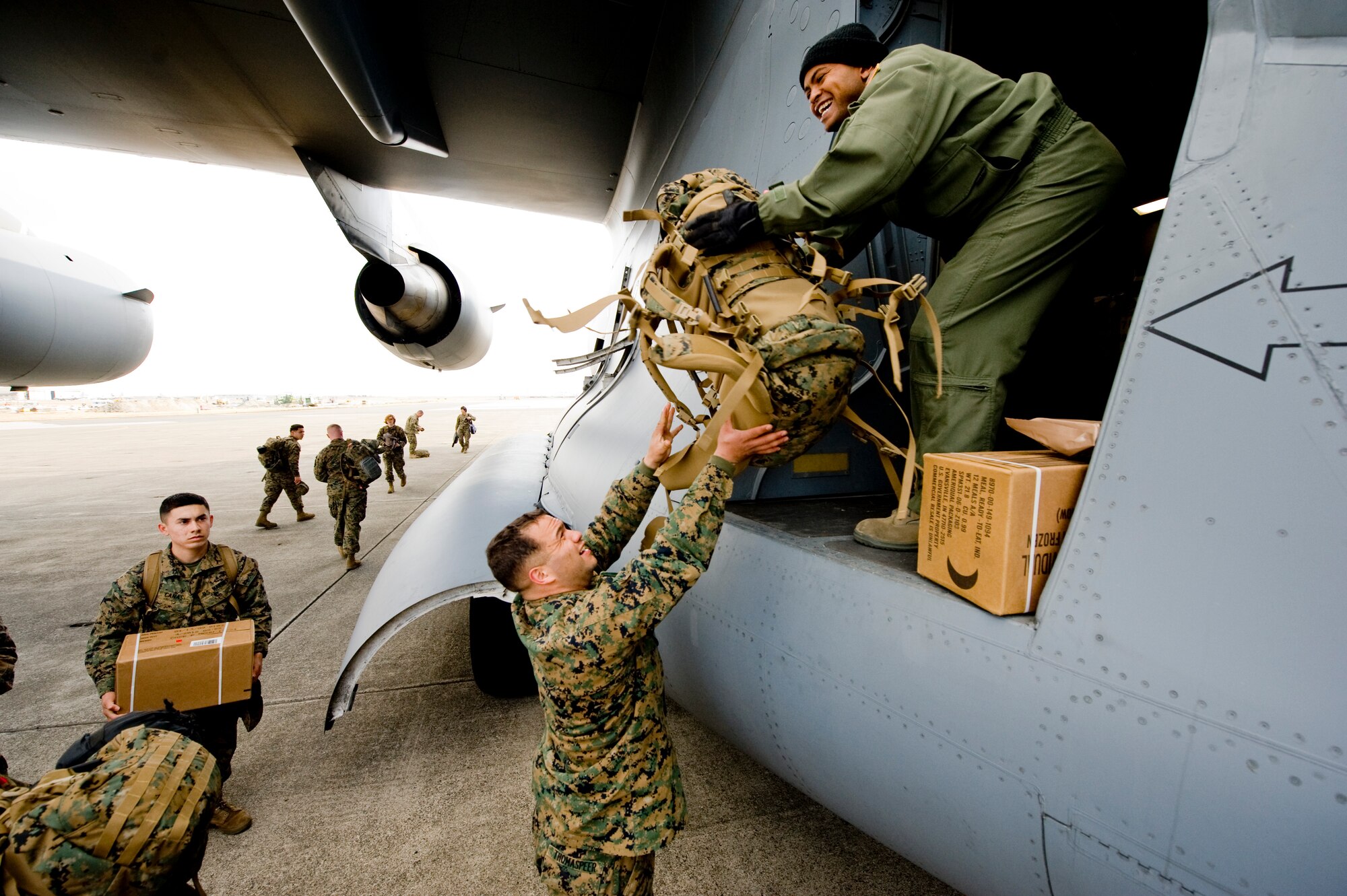 MARINE CORPS AIR STATION IWAKUNI, Japan -- A U.S. Marine from Marine Wing Support Squadron 171 hands his bag to Tech. Sgt. Ike Murray, 535th Airlift Squadron, on board a C-17 Globemaster III March 25, 2011. The C-17 crew flew into Marine Corps Air Station Iwakuni to pick up Marines from Marine Wing Support Squadron 171 and drop them off at Sendai Airport. The Marines travelled to Sendai Airport to setup portable showers for Japanese citizens as part of the humanitarian assistance provided during Operation Tomodachi. (U.S. Air Force photo/Staff Sgt. Jonathan Steffen)