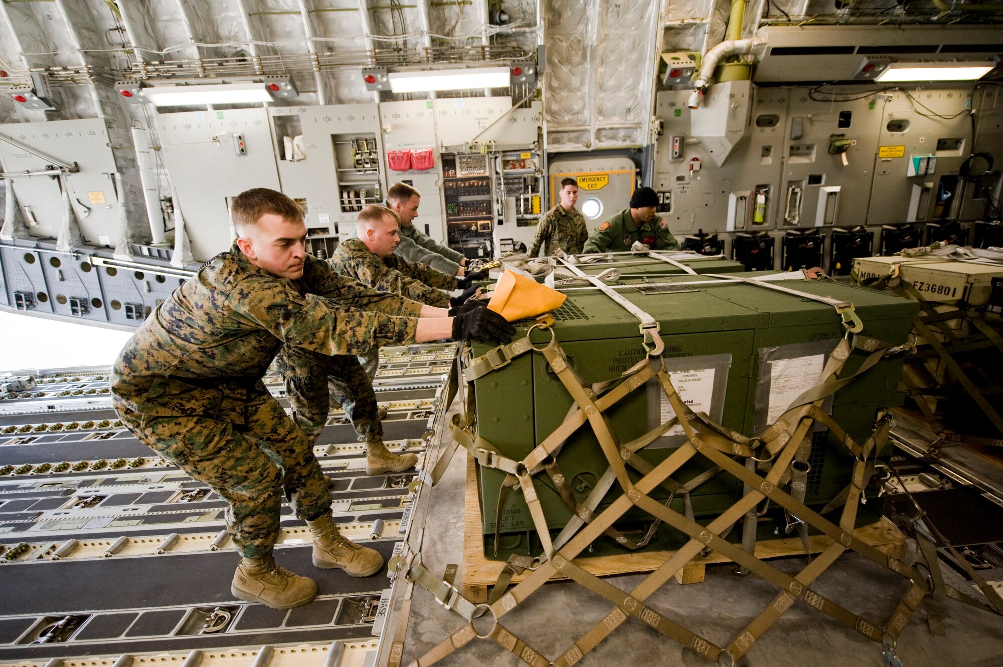 MARINE CORPS AIR STATION IWAKUNI, Japan --  U.S. Marines and Airmen pushes a pallet of supplies on board a C-17 Globemaster III March 25, 2011. The C-17 crew flew into Marine Corps Air Station Iwakuni to pick up Marines from Marine Wing Support Squadron 171 and drop them off at Sendai Airport. The Marines travelled to Sendai Airport to setup portable showers for Japanese citizens as part of the humanitarian assistance provided during Operation Tomodachi. (U.S. Air Force photo/Staff Sgt. Jonathan Steffen)
