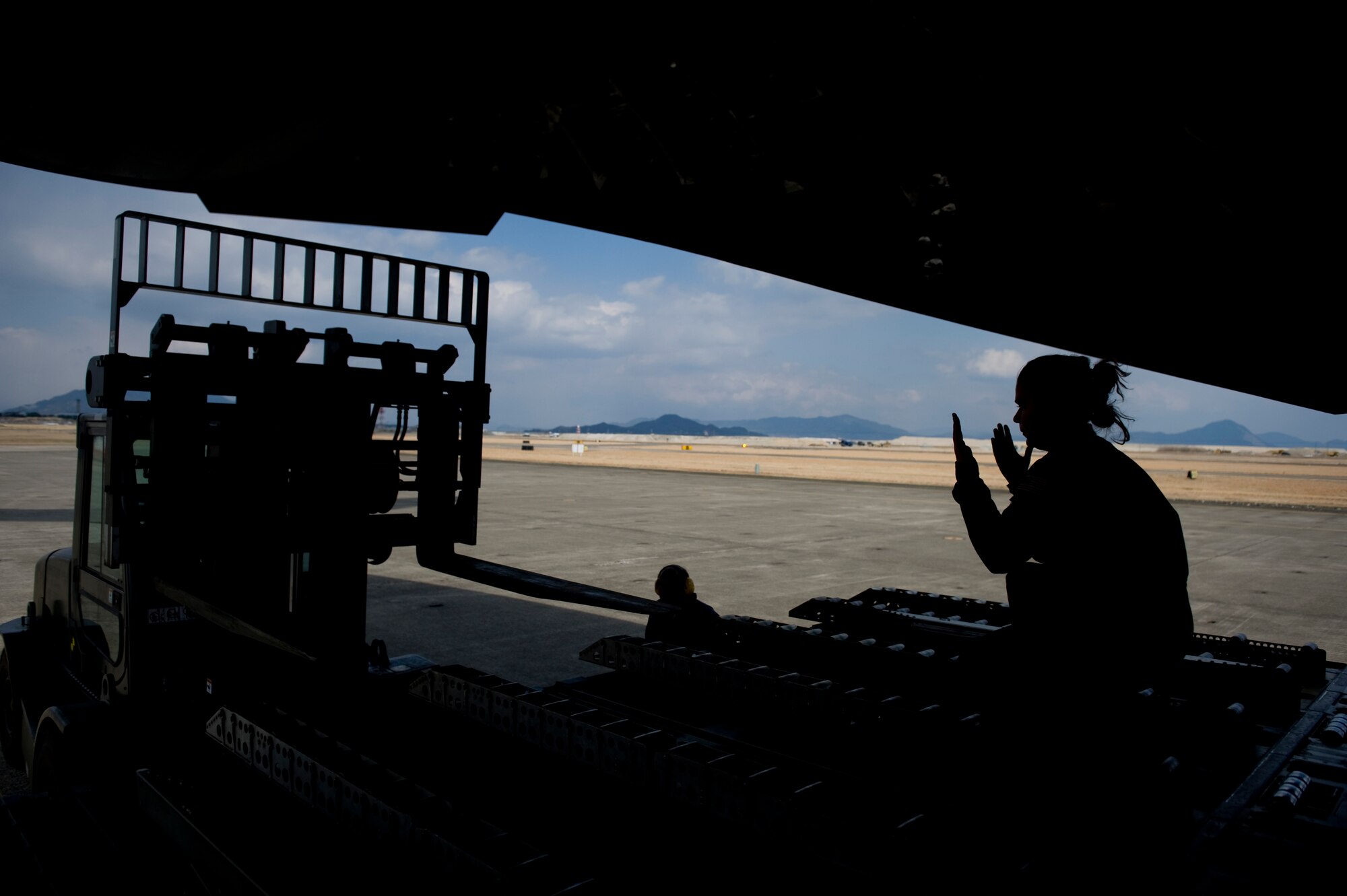 MARINE CORPS AIR STATION IWAKUNI, Japan -- Senior Airman Kristina Cyphert, 535th Airlift Squadron, directs a forklift while offloading cargo from a C-17 Globemaster III March 25, 2011. The C-17 crew flew into the air station to pick up Marines from Marine Wing Support Squadron 171 and drop them off at Sendai Airport. The Marines travelled to Sendai Airport to setup portable showers for Japanese citizens as part of the humanitarian assistance provided during Operation Tomodachi. (U.S. Air Force photo/Staff Sgt. Jonathan Steffen)