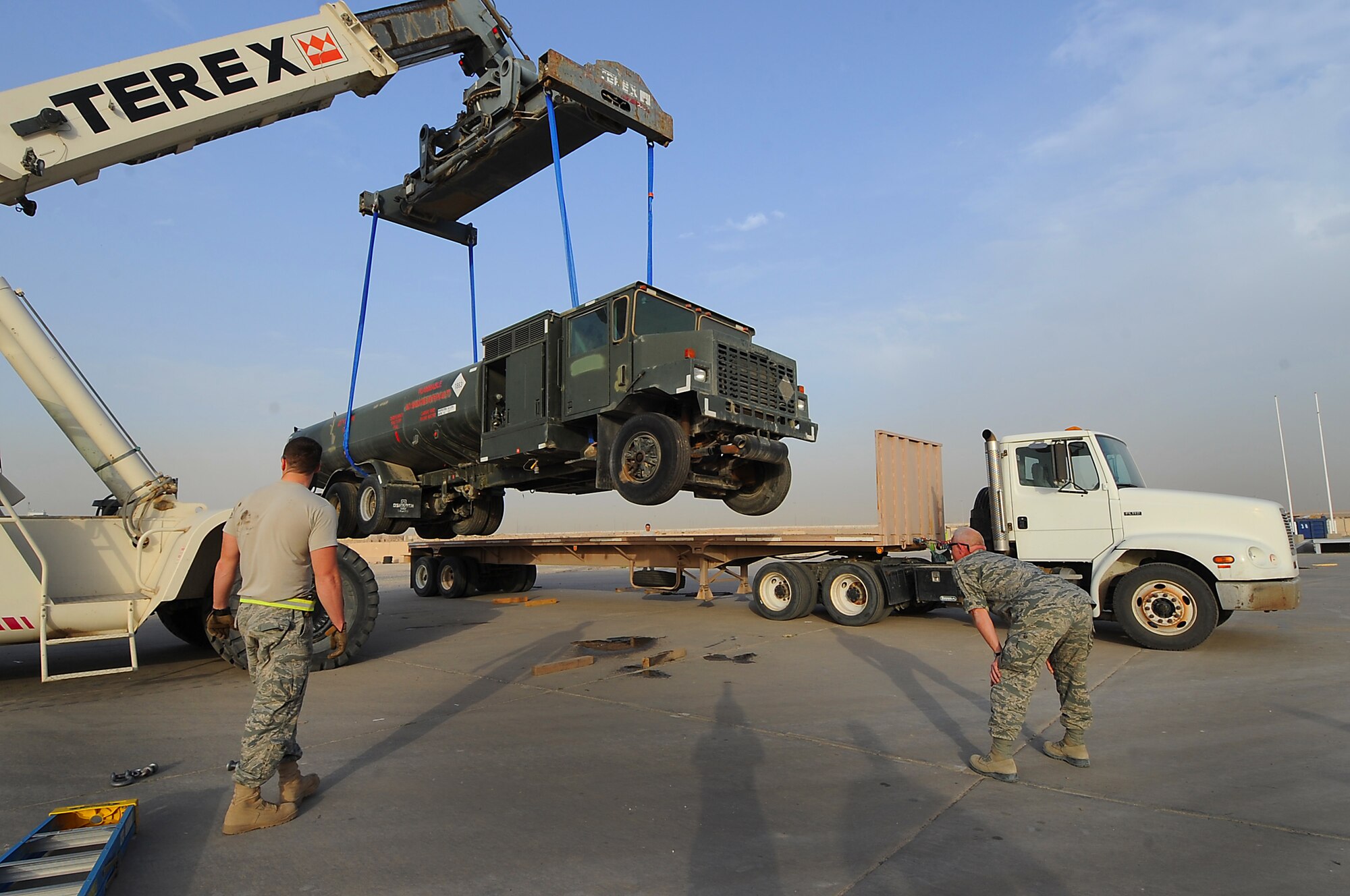 Senior Master Sgt. John Robinson and Staff Sgt. Jimmy Boulware guide the terex operator in loading an R-11 Refueler onto a flatbed for transport March 22. Sergeant Robinson is the deployed distribution superintendent and Sergeant Boulware is a vehicle operator, both with the 386th Expeditionary Logistics Readiness Squadron. (U.S. Air Force photo by Senior Airman Cynthia Spalding)