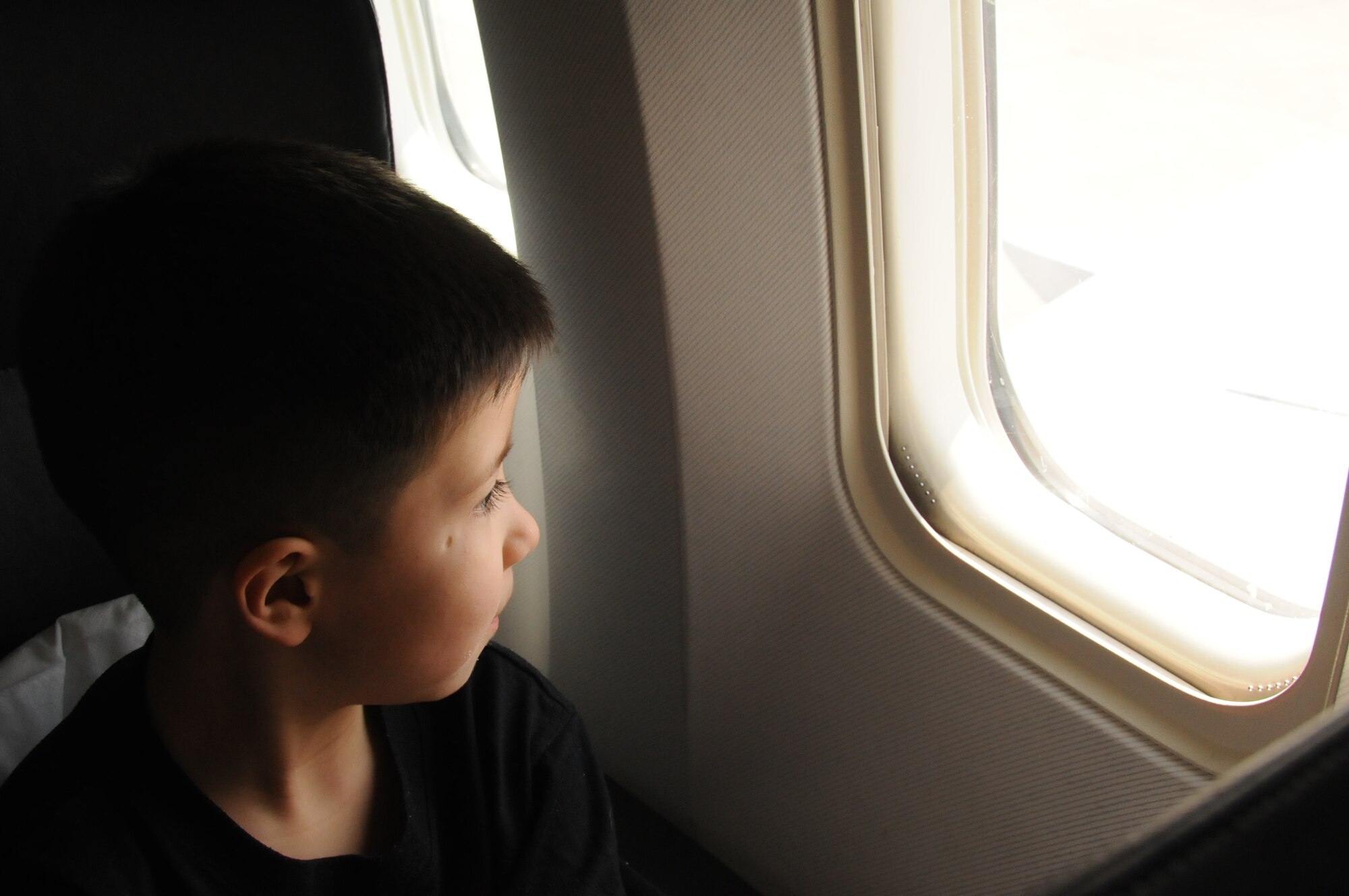 MISAWA AIR BASE, Japan -- Damian Sanchez, 5-year-old son of Airman 1st Class Emanuel Sanchez, 35th Maintenance Squadron, looks out the aircraft window prior to departing Misawa March 25. Damian and his mother, Belinda Sanchez, are headed to Texas as part of the Department of Defense-approved voluntary departure for families affected by the March 11 earthquake. Damian “has been dealing with things quite well. He just doesn’t understand why we can’t do certain things because of the earthquake,” said Mrs. Sanchez. (U.S. Air Force photo by Staff Sgt. Rachel Martinez/Released)