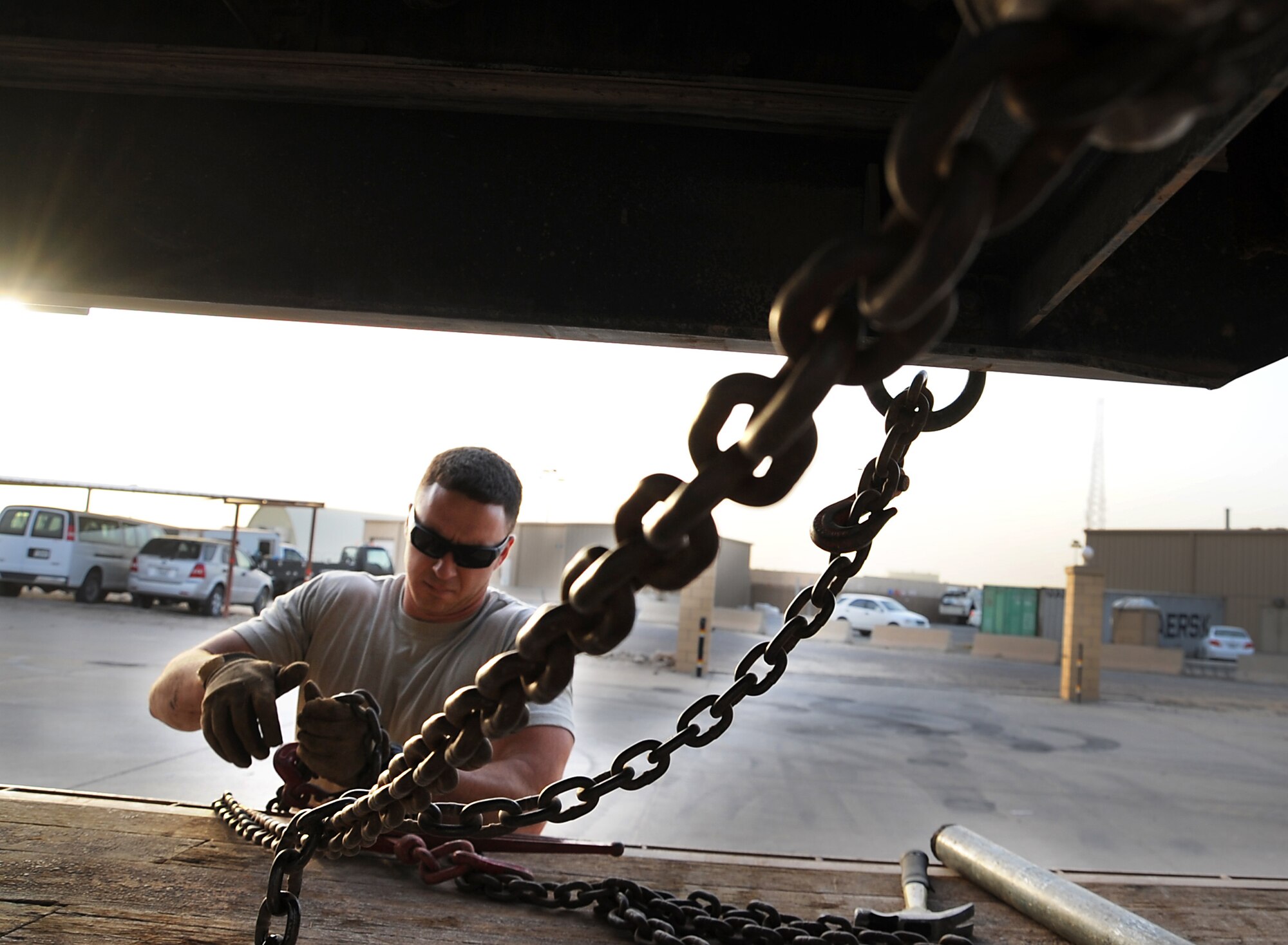 Staff Sgt. Jimmy Boulware hooks up a load binder to a tie down chain for securing an R-11 Refueler to a flatbed before transport March 22. Load binders take the extra slack out of chains when tightening for a secure load. Sergeant Boulware is a vehicle operator with the 386th Expeditionary Logistics Readiness Squadron. (U.S. Air Force photo by Senior Airman Cynthia Spalding)
