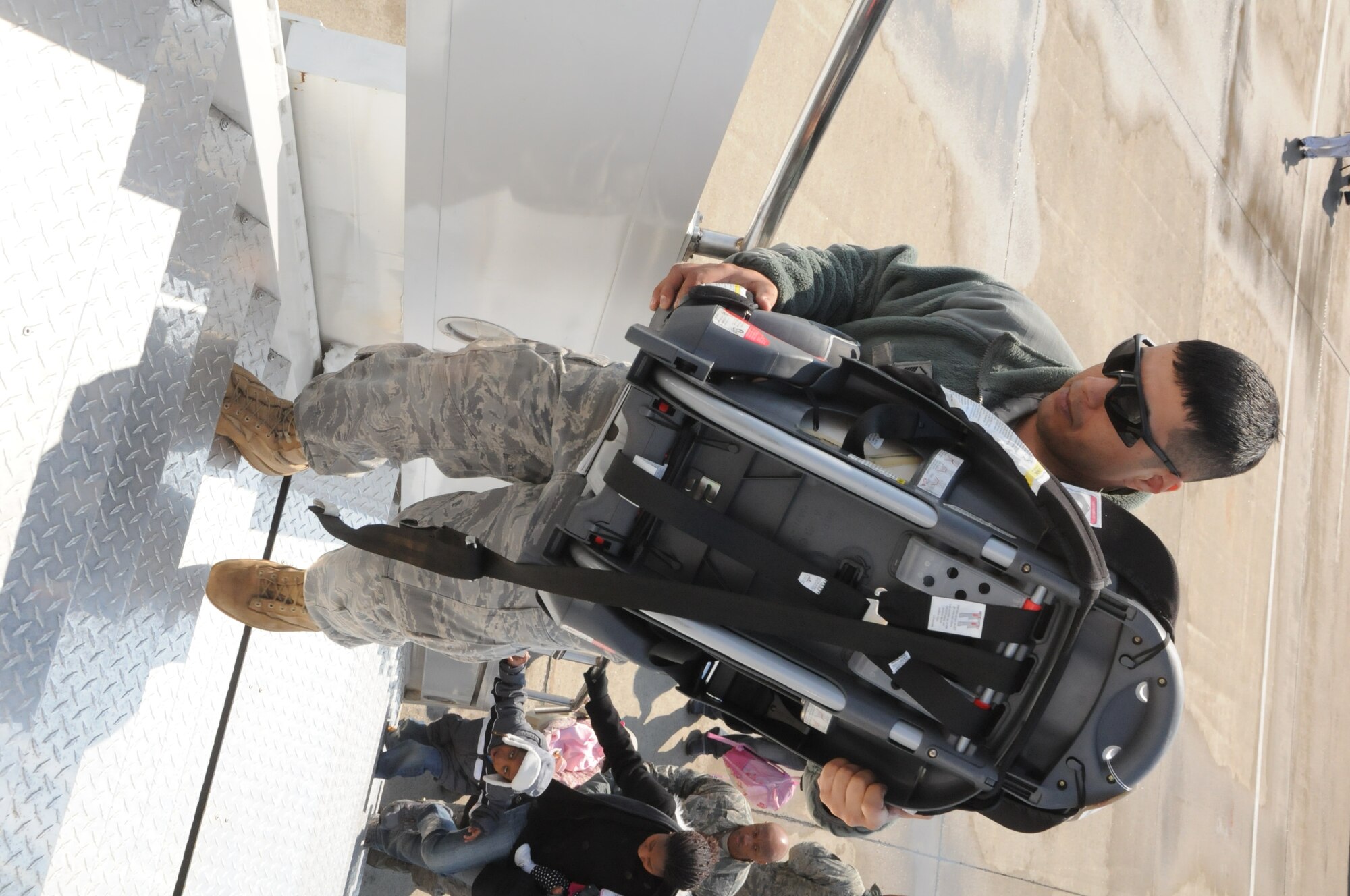 MISAWA AIR BASE, Japan -- Master Sgt. Alexander Arias, 35th Logistics Readiness Squadron, carries a car seat onto a the aircraft for a departing family member. Airmen from around the base assisted with luggage and children throughout the entire voluntary departure process in an effort to make it as easy as possible for the families. (U.S. Air Force photo by Staff Sgt. Rachel Martinez/Released)