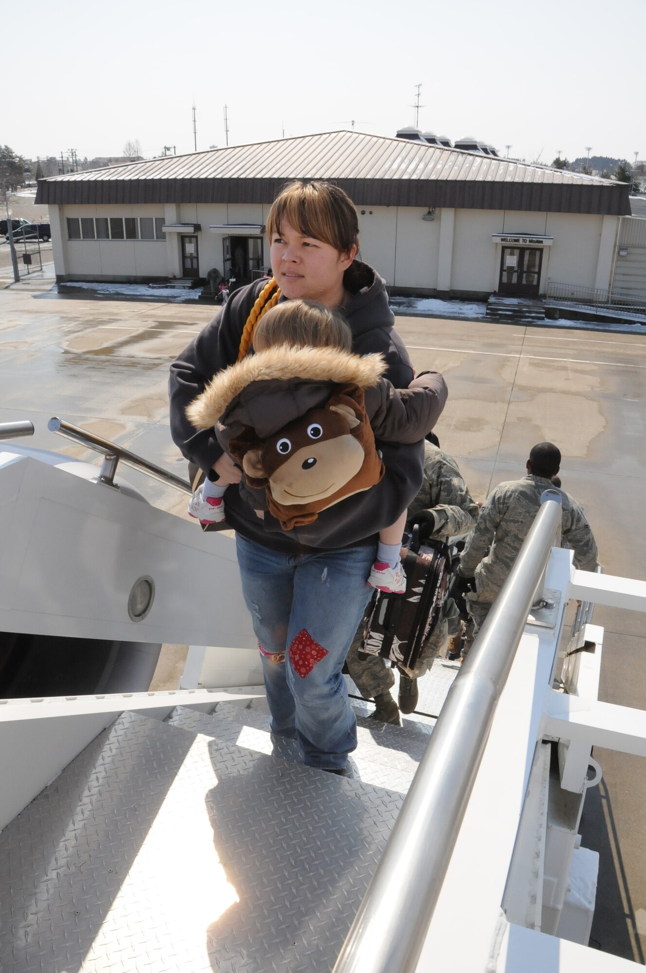 MISAWA AIR BASE, Japan -- Family members leaving as part of the Department of Defense voluntary departure, climb the stairs to an aircraft, March 25. Six aircraft have departed Misawa, carrying more than 1,300 family members to the U.S. (U.S. Air Force photo by Staff Sgt. Rachel Martinez/ Released)
