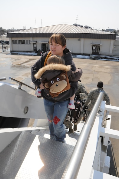 MISAWA AIR BASE, Japan -- Family members leaving as part of the Department of Defense voluntary departure, climb the stairs to an aircraft, March 25. Six aircraft have departed Misawa, carrying more than 1,300 family members to the U.S. (U.S. Air Force photo by Staff Sgt. Rachel Martinez/ Released)