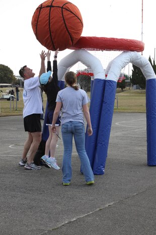 The Saunders family tries to put an oversized basketball into a giant hoop at the basketball court near the skate park here for the Amazing Race Family Edition March 26. Each family member on the team had to make a basket before moving on. While taller participants had no problem making baskets, younger ones needed assistance as they struggled with the ball twice their size.