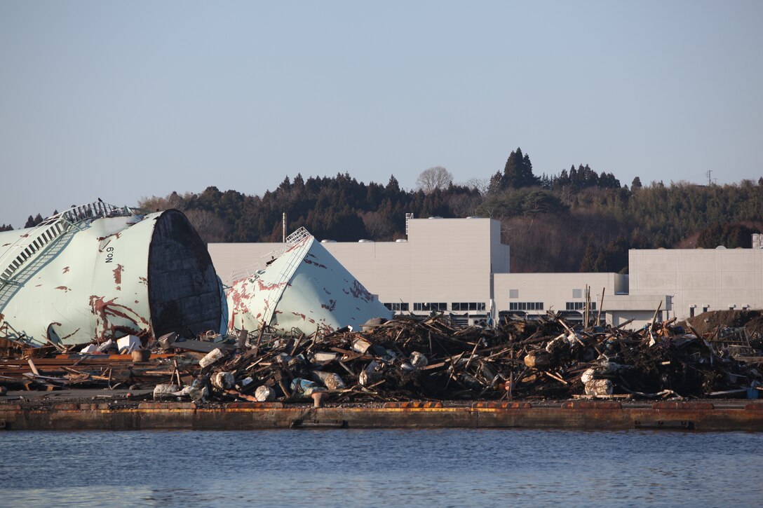 Petroleum tanks and buildings lie damaged in the port here, March 27, the result of the 9.0 earthquake and tsunami.  The 31st Marine Expeditionary Unit and Amphibious Squadron 11 delivered food, water, comfort items and commercial repair vehicles to residents on the isolated island of Oshima using U.S. Navy landing craft, demonstrating the MEU’s expeditionary capabilities in ship-to-shore amphibious operations. Marines and Sailors of the 31st MEU are conducting humanitarian aid and disaster relief missions in northeast Japan in coordination with the Japanese Self Defense Forces.