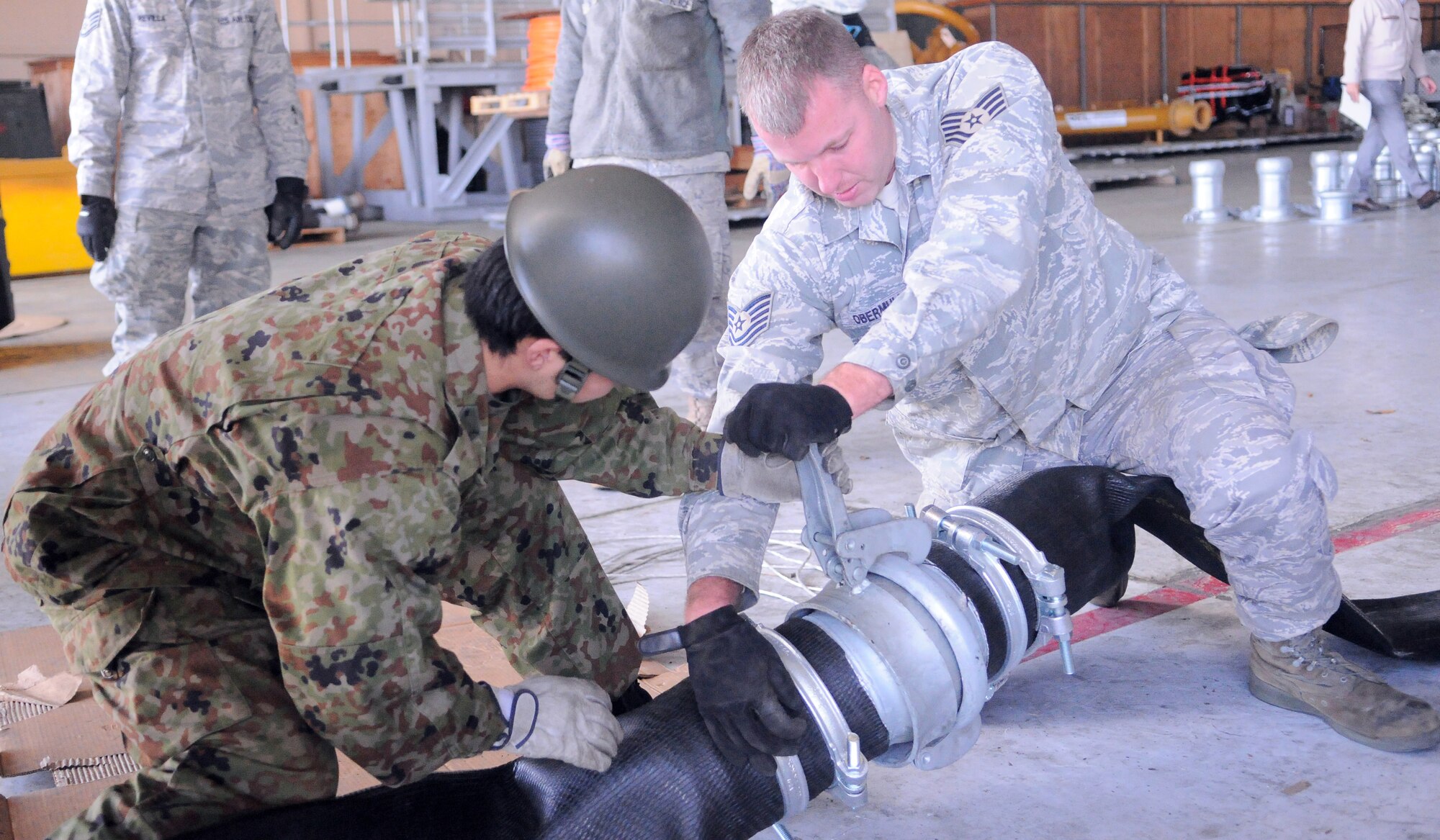 YOKOTA AIR BASE, Japan -- Tech. Sgt. John Obermuller, 374th Maintenance Squadron, and a Japan Ground Self-Defense Force member join two sections of hose March 26, 2011.  The hoses are part of water pump donated by the US government to help the Japanese government stabilize the Fukushima nuclear power plant. The entire system was flown to Yokota and will soon be transported to the reactor site.  (U.S. Air Force photo/Airman 1st Class Krystal M. Garrett)  