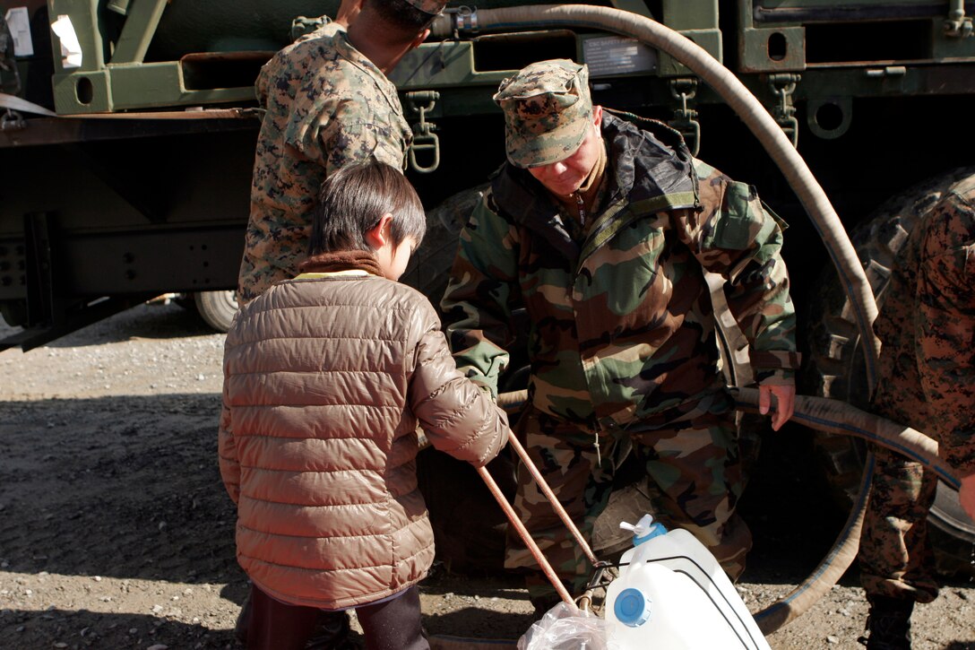 A Sailor with Amphibious Squadron 11 hands a girl a water jug, March 27. The 31st Marine Expeditionary Unit delivered food, water, health and comfort supplies, and Japanese electrical utility vehicles to the isolated island of Oshima, in conjunction with Japanese Self-Defense Forces. The 31st MEU’s involvement is part of a larger U.S. government response, after a 9.0 earthquake and subsequent tsunami struck Japan causing widespread damage. The 31st MEU is ready to support our Japanese partners and to provide assistance when called upon.