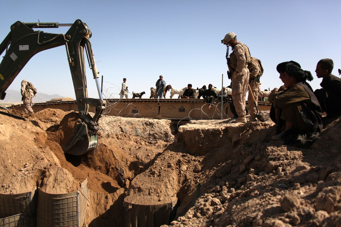 U.S. Marine Corps 1st Lt. Daniel Hough, platoon commander of Engineer Platoon, Battalion Landing Team 3/8, Regimental Combat Team 8, and local Afghans watch as Marines remove a bridge and culvert at Kakar village, Helmand province, Afghanistan, March 28, 2011. Residents asked the Marines to build the bridge then asked them to removed it a few days later in the erroneous belief it hindered water flow to their poppy fields. Despite assurances from the engineers that the water was unrestricted, the Marines removed the bridge at local Afghans' insistence in order to maintain the goodwill, trust and confidence the Marines have earned since their arrival. Elements of 26th Marine Expeditionary Unit deployed to Afghanistan to provide regional security in Helmand province in support of the International Security Assistance Force. ( U.S. Marine Corps photo by Gunnery Sgt. Bryce Piper/Released)::r::::n::