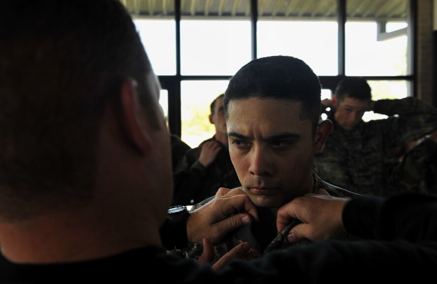 MOODY AIR FORCE BASE, Ga.-- Capt. Adrian Simental, 49th Materiel Maintenance Support Squadron operations officer, Holloman AFB, N.M.,  has his collar tucked in by an instructor March 23. Captain Simental participated in a water confidence portion of the air liaison officer training course where individuals learned how to float using their ABU or BDU tops. (U.S. Air Force photo/Airman 1st Class Joshua Green)(RELEASED)
